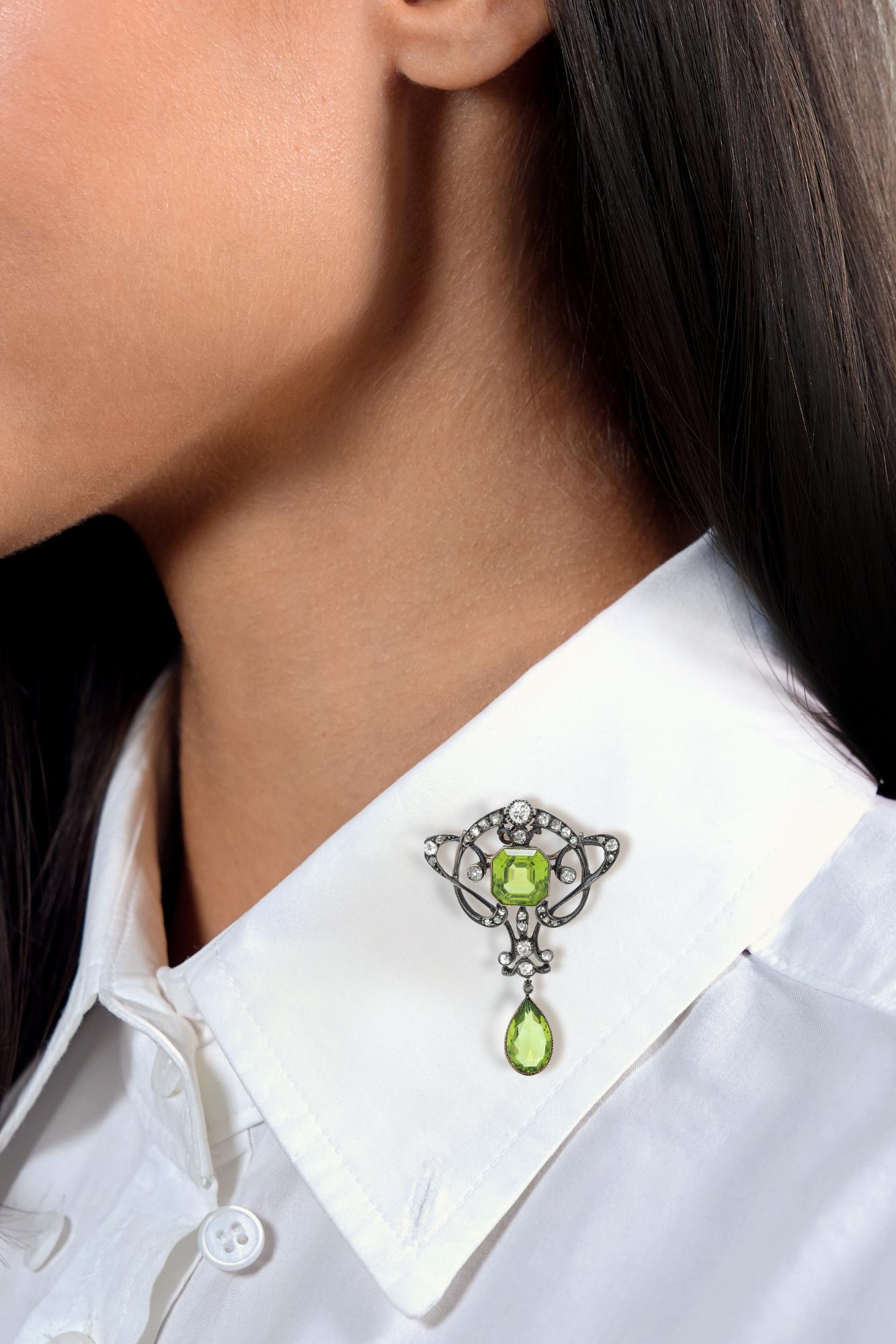 Designed as pierced silver-topped whiplash motif centering an emerald cut peridot
Weighing approximately 5.08 - transparent medium yellowish green in color
Bezel set and well-matched to articulating pear cut peridot drop
Weighing approximately 3.02