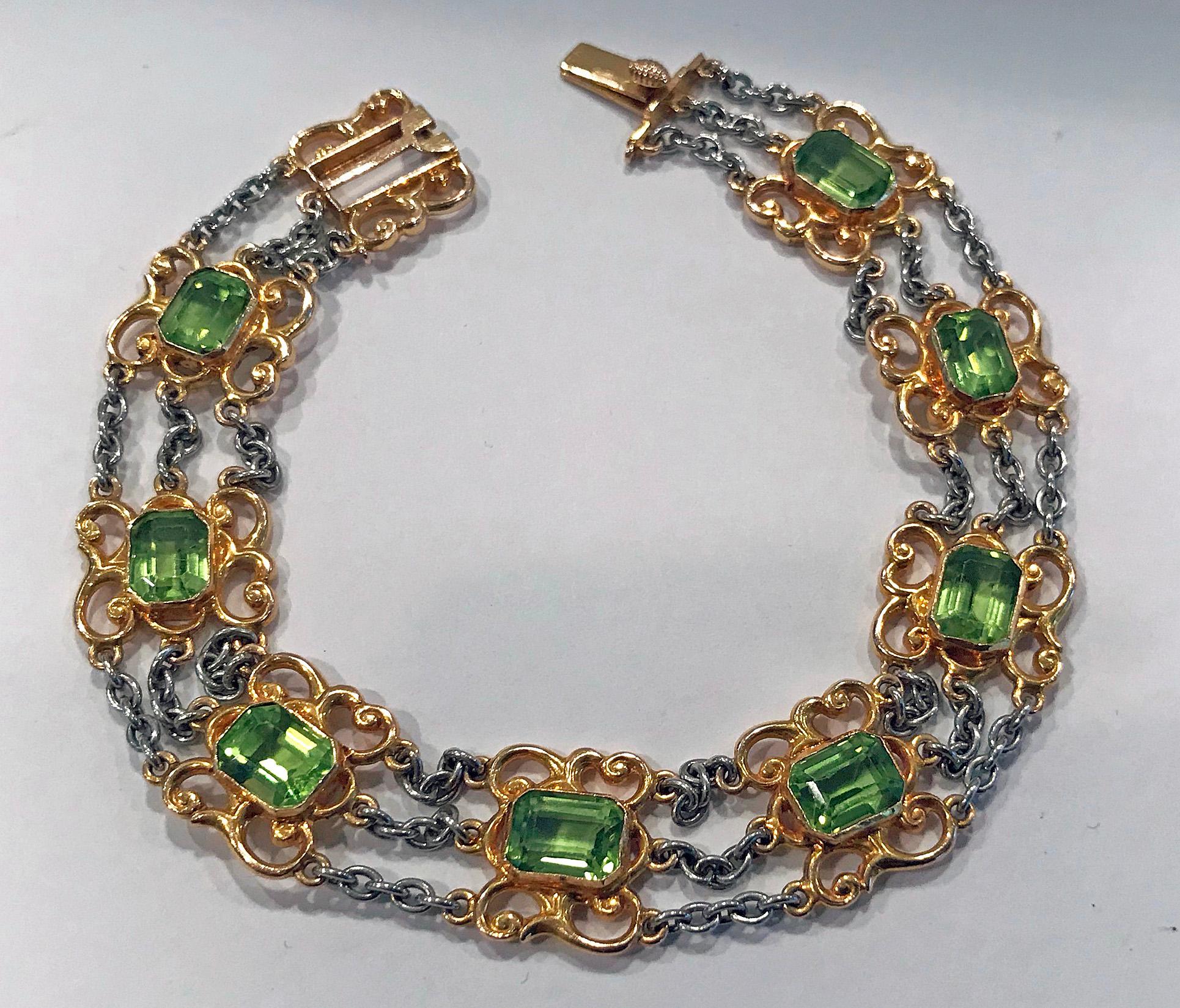 Very fine Art Nouveau Peridot Gold and Platinum Bracelet, C.1910. The Bracelet bezel set with eight emerald cut fine peridot, each gauging approximately 7.5 x 5.5 x 4.6 mm. Art Nouveau open scroll surround and triple link platinum links between,