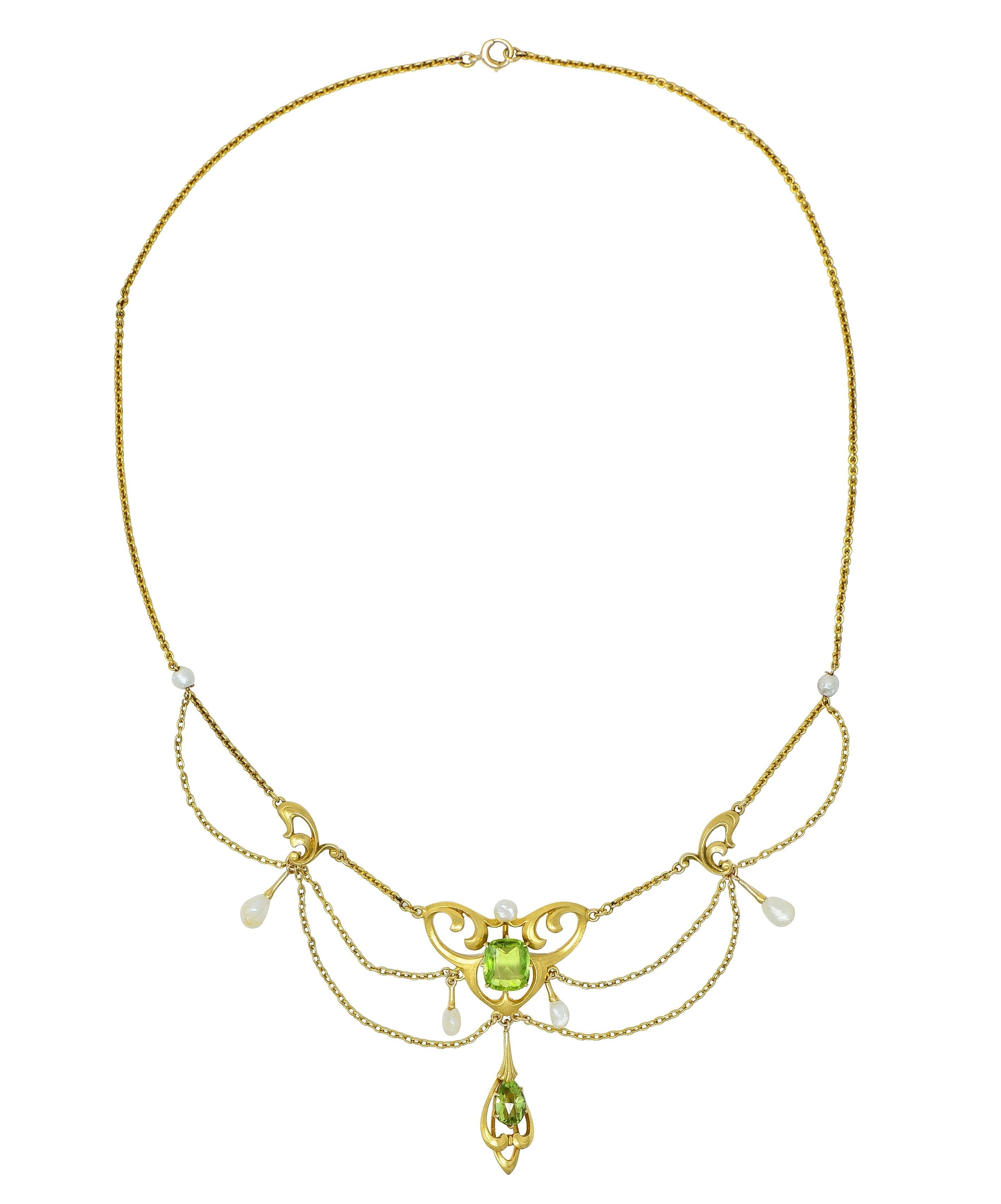 Designed as a cable link chain featuring a swagged station centering a cushion cut peridot
Weighing approximately 1.94 carats - transparent medium yellowish-green in color 
Prong set with a flowing whiplash motif surround and suspending whiplash
