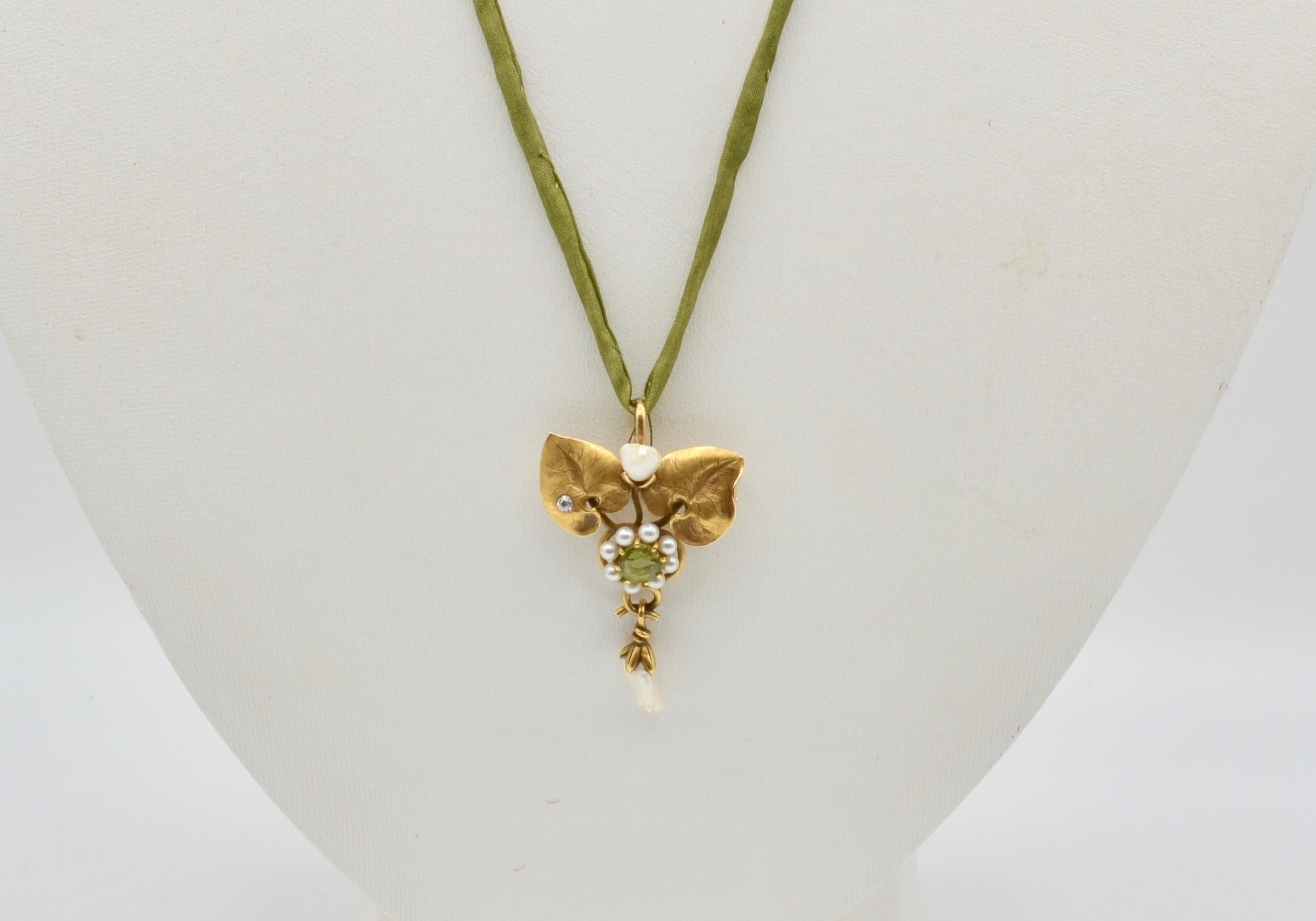 This nature inspired pin/pendant is a beautiful depiction of a floral motif set in 14 karat yellow gold. The  (0.04  carat ) diamond, (0.35 carat ) peridot, and freshwater pearl motif. The yummy green 17 1/4