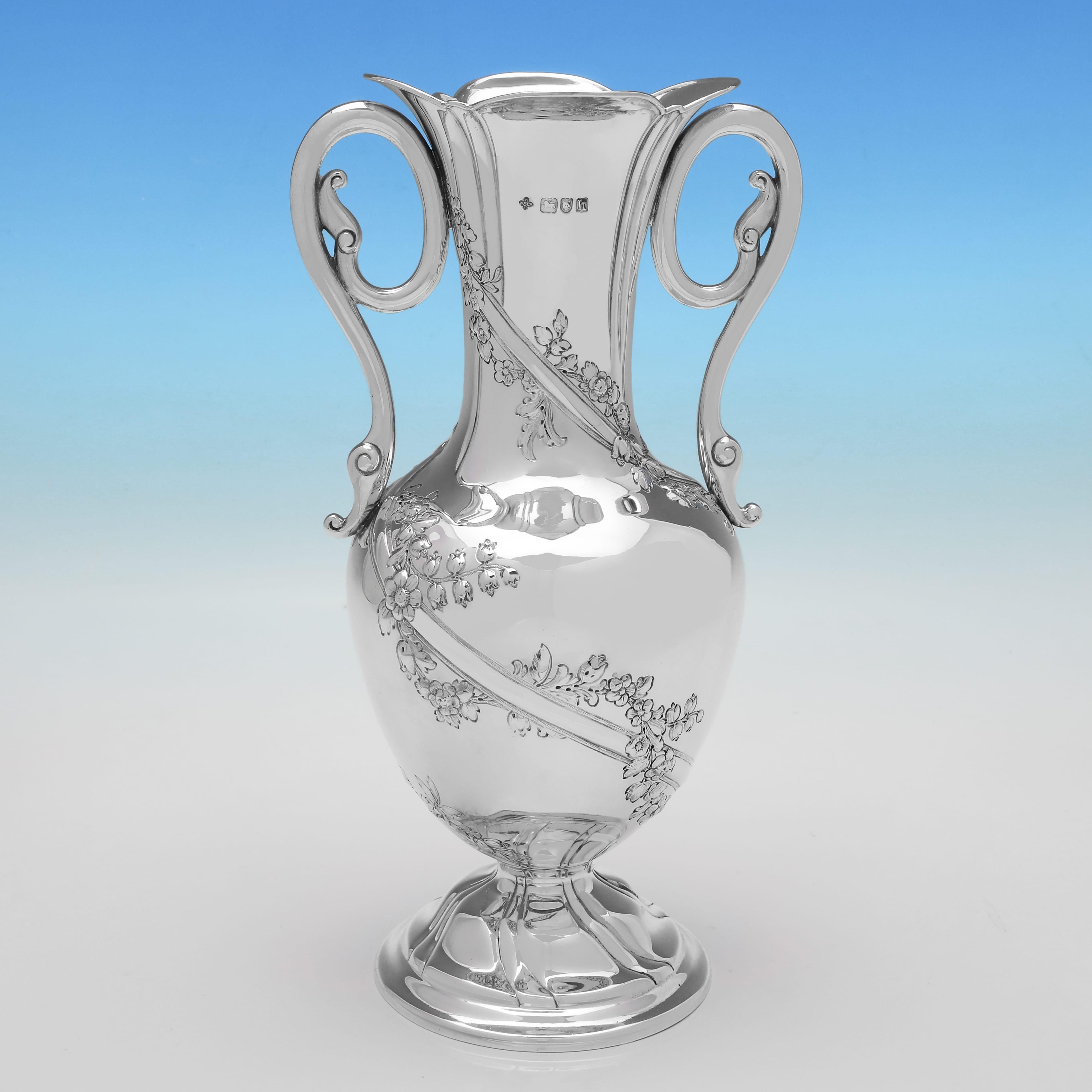 Marchiata a Londra nel 1903 da William Hutton & Sons, questa attraente coppia di vasi antichi in argento sterling di epoca edoardiana presenta decorazioni floreali e di viti sul corpo e manici a voluta. Ciascun vaso misura 11