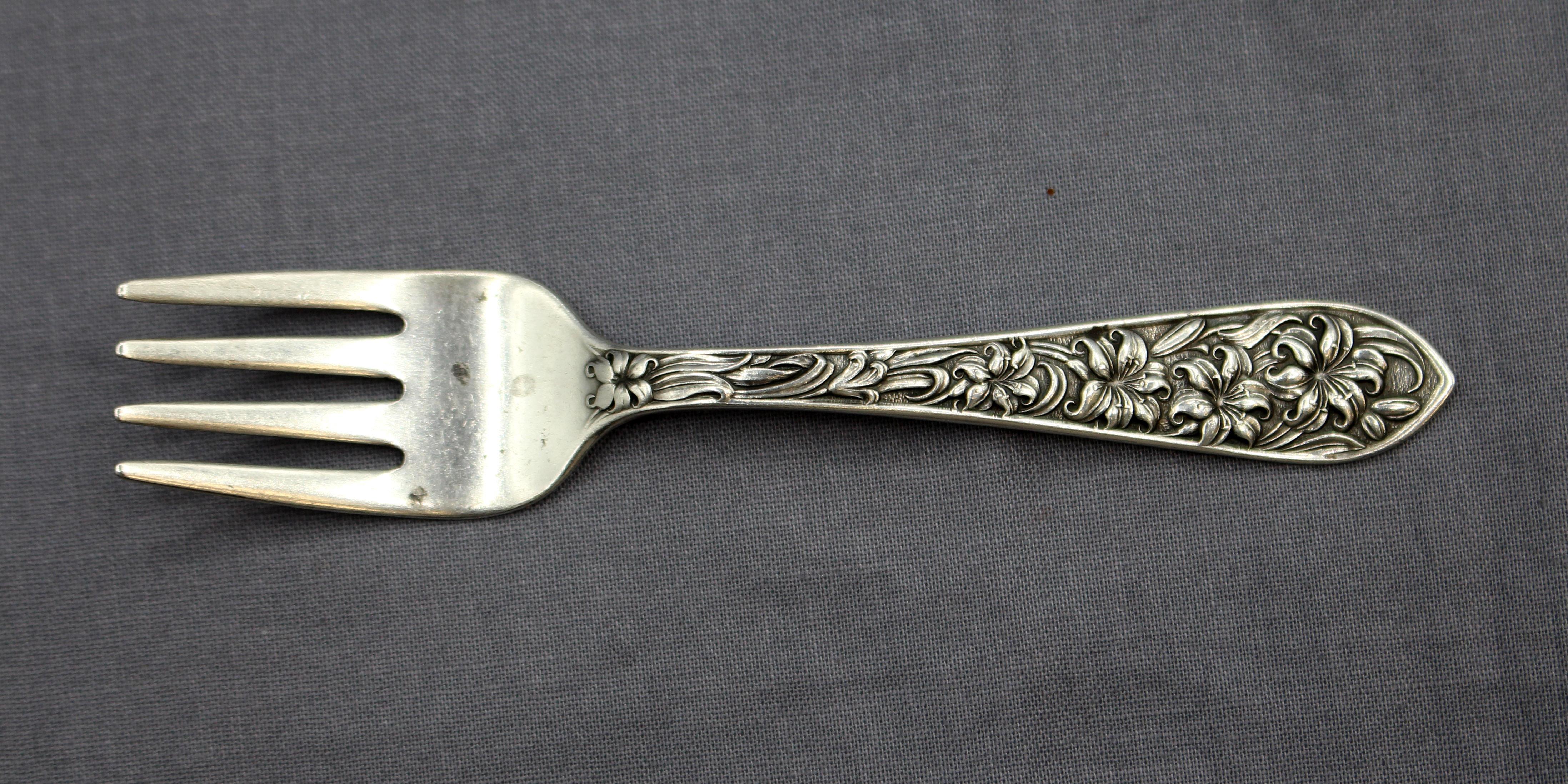 Empujador y tenedor para comida de bebé de plata de ley de la época Art Nouveau por F.M. Whiting. Patrón Lirio de Pascua. Raro, nunca grabado y encantador. Marcado: Frank M Whiting Sterling. 1 onza troy. Horquilla: 4,5