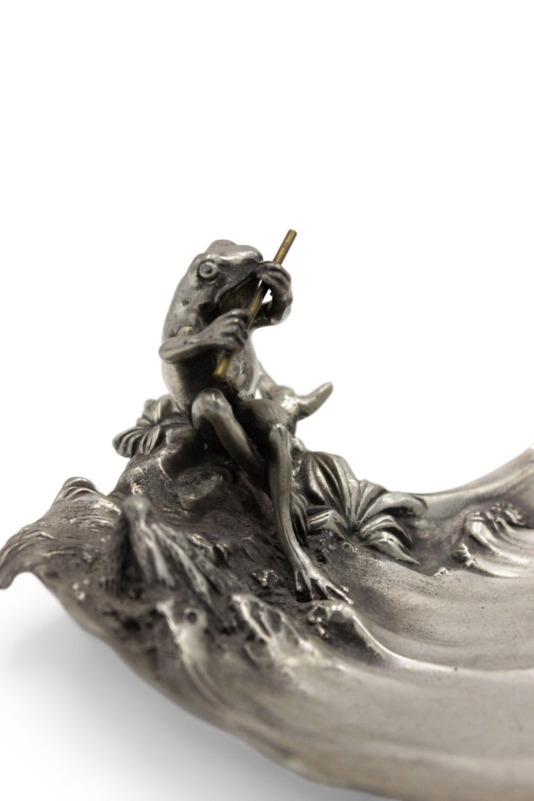 Art Nouveau-style (German) pewter ashtray in the form of a pond with a frog sitting on the edge playing a flute (Stamped with hallmarks: ACHILE GAMBA).
  