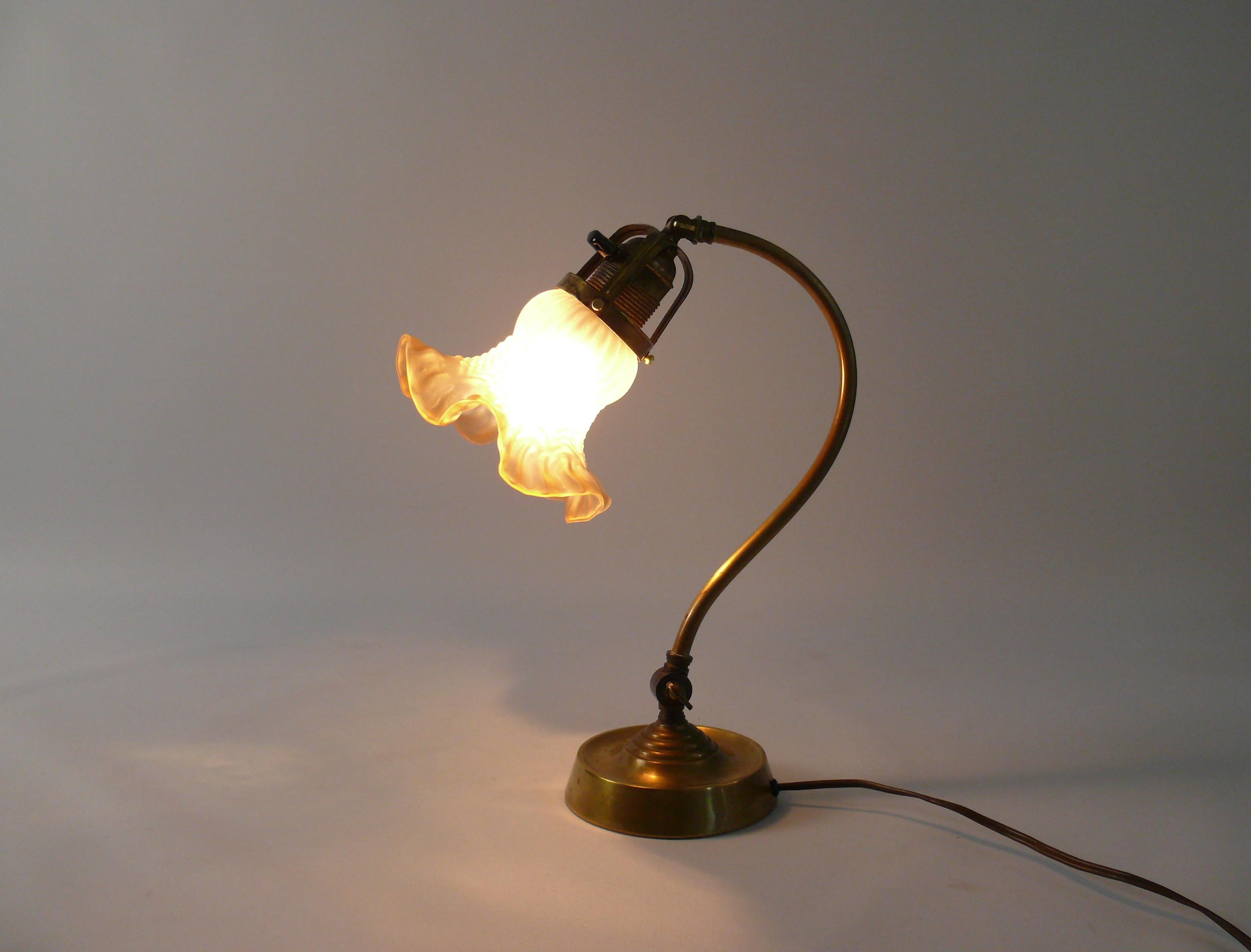 Original Art Nouveau table lamp from the 1920s in good working condition, can also be used as a Piano Lamp. The lamp consists of a stable brass base with a metal core and a flower-shaped glass shade. The screen is in good condition. It can be