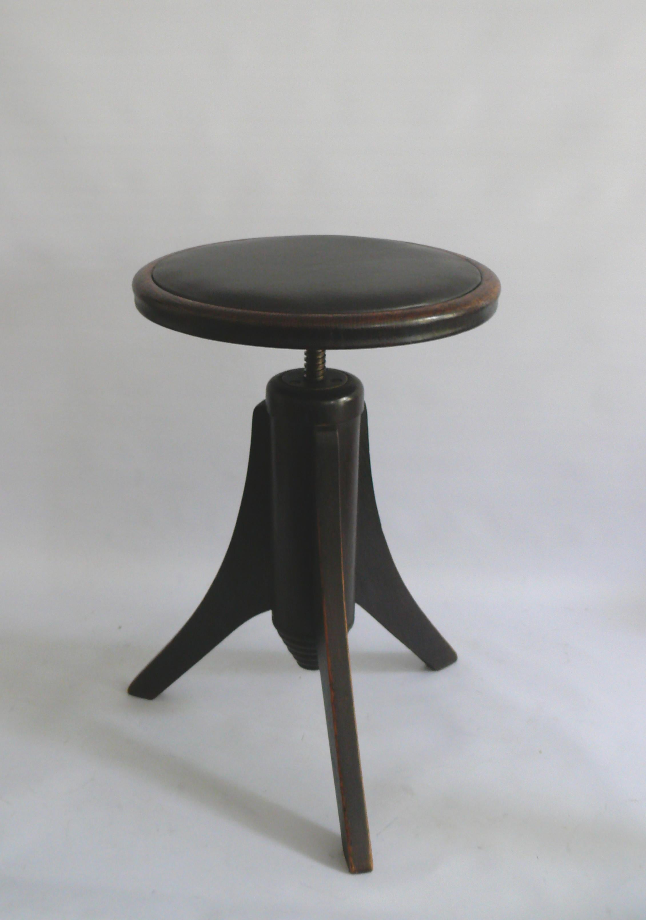 Elegant piano stool/swivel stool in dark walnut with a padded seat. The piano stool is made of solid wood – probably walnut or beech – and has three tapered legs. The stool can be adjusted in height from approximately 50 cm to 65 cm using a metal