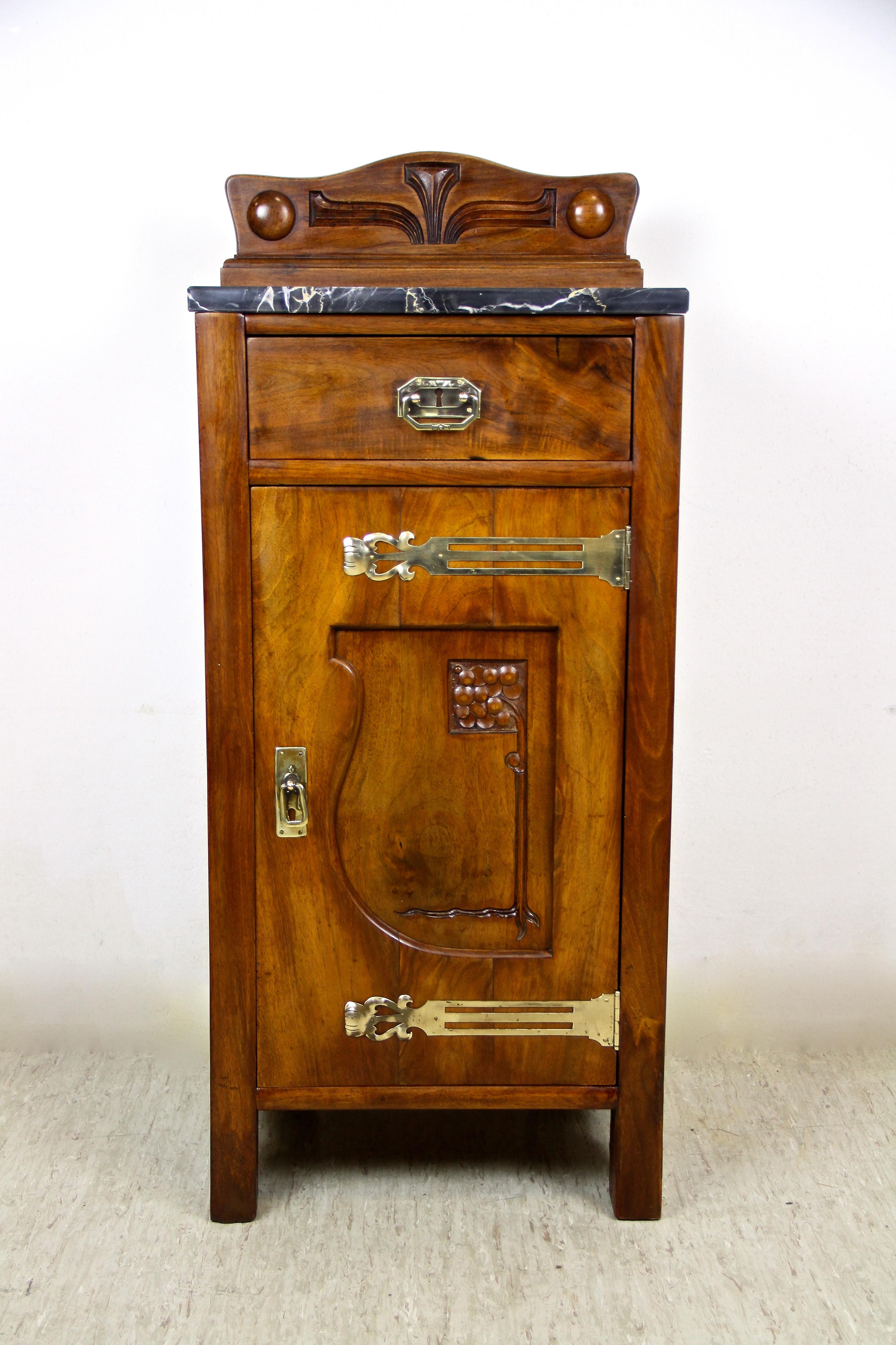 Charming Art Nouveau pillar commode from the very early 20th century in Austria. Made around 1905, this eye-catching compact pillar commode shows a lovely nut wood veneered surface adorned by beautiful brass applications. The door, adorned by an