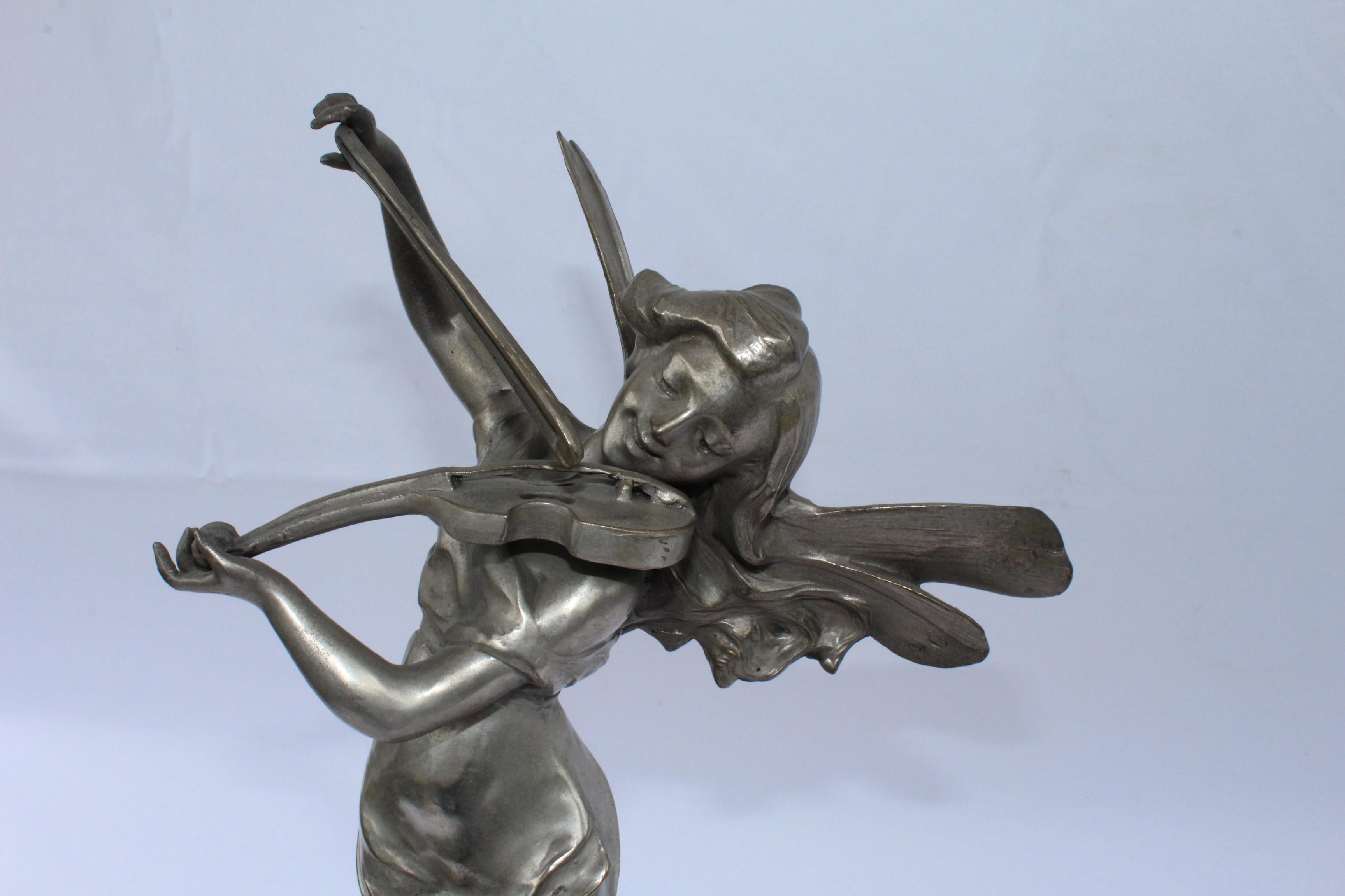 A fantasy figurine of a young girl Pixy playing the Violin. Standing on a pedestal with Cherubs all around with silver patina finish. All mounted on absolute Black marble base. Bears the sign of Aug Moreau. At 21