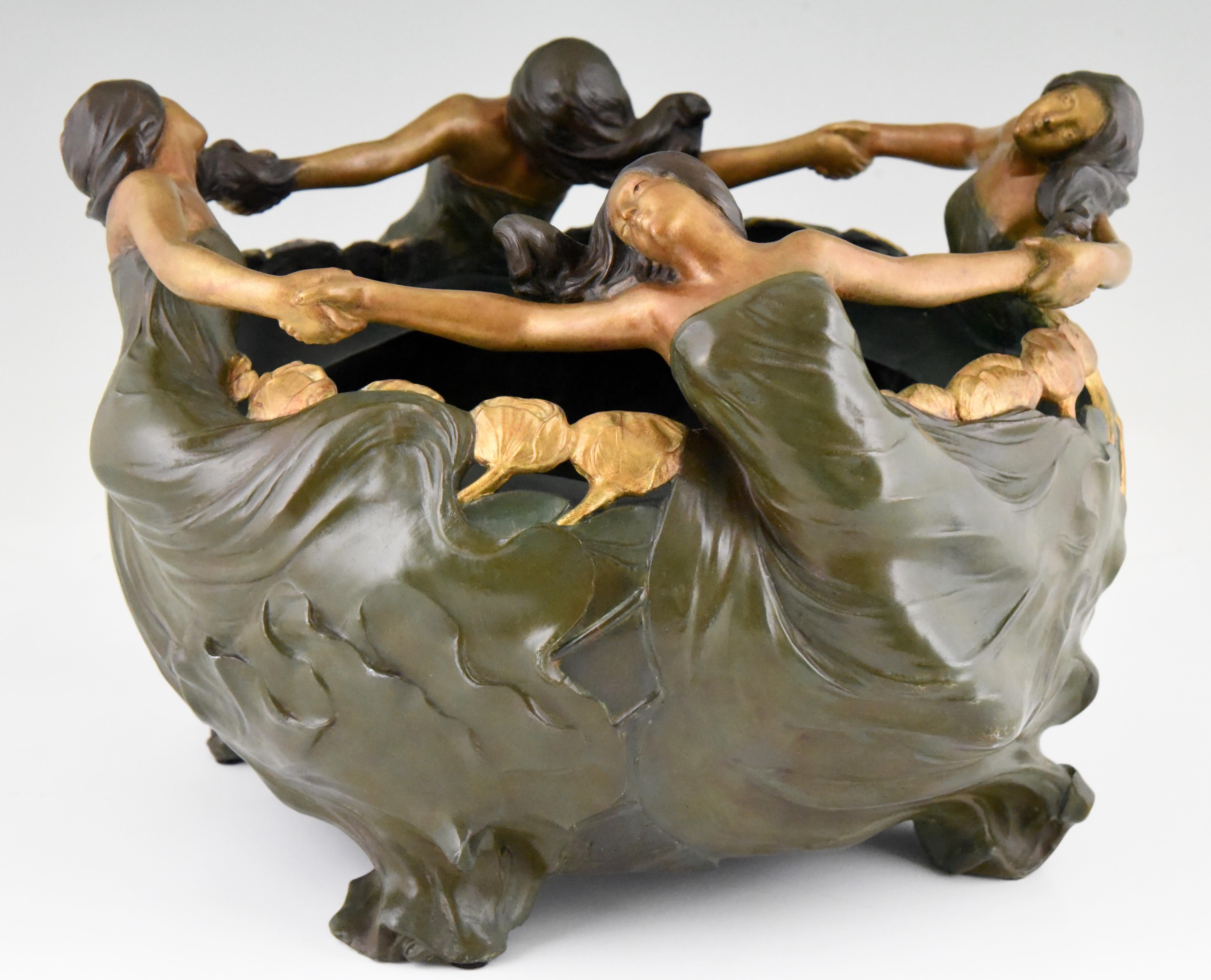 La Ronde, Art Nouveau cachepot, jardiniere or planter with dancing women in long dresses. The surface is decorated with flowers.
Signed by Louis Eugene Maurel, born in Paris in 1880. 
The pewter flower dish has a beautiful multi color patina.