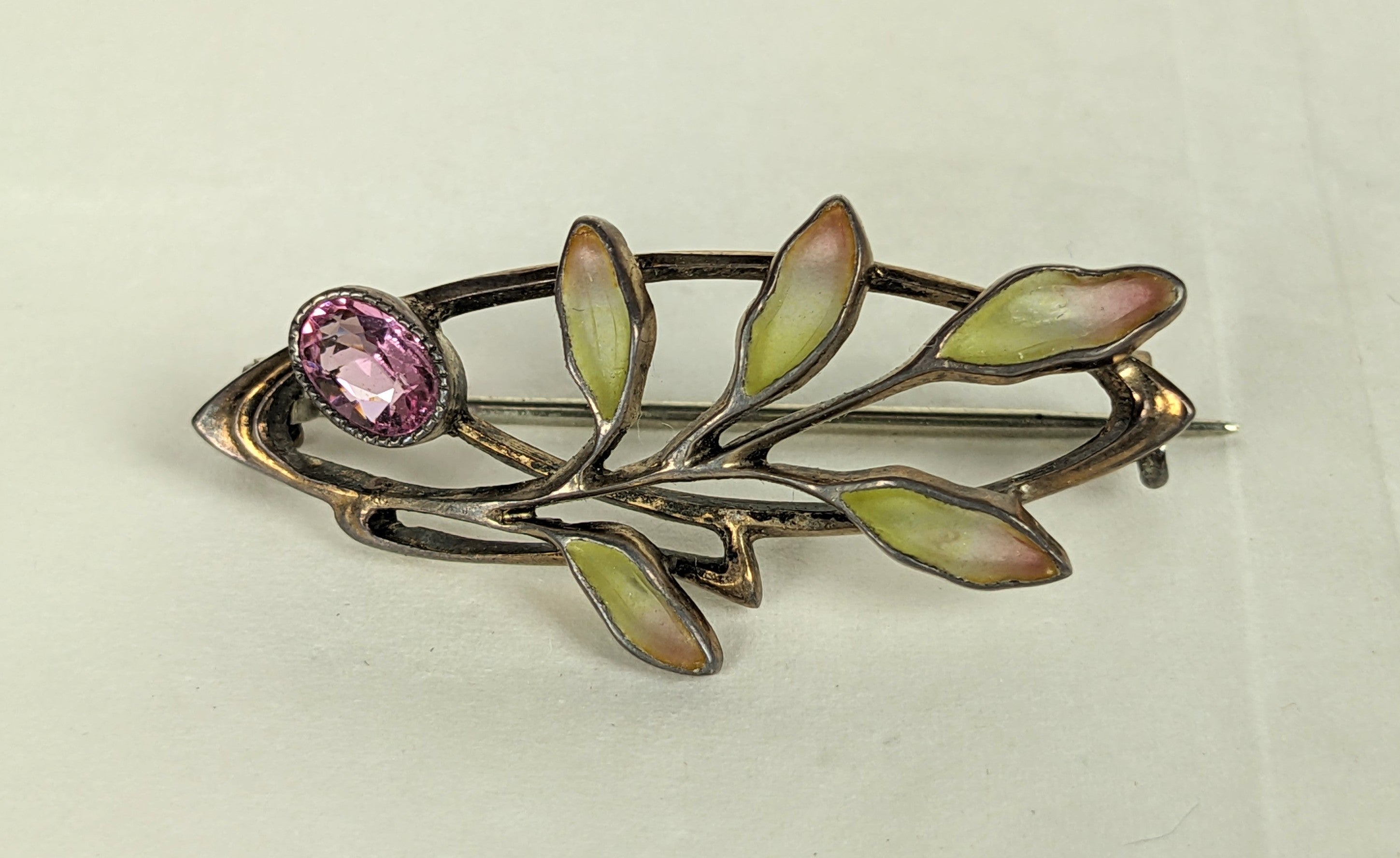 Lovely Art Nouveau Plique a Jour Brooch from the early 20th Century of vermeil sterling. A spray of plique green to rose enamel leaves with pink gem or crystal stone. Likely German in origin, marked Sterling. 1900's Eu. 1.5