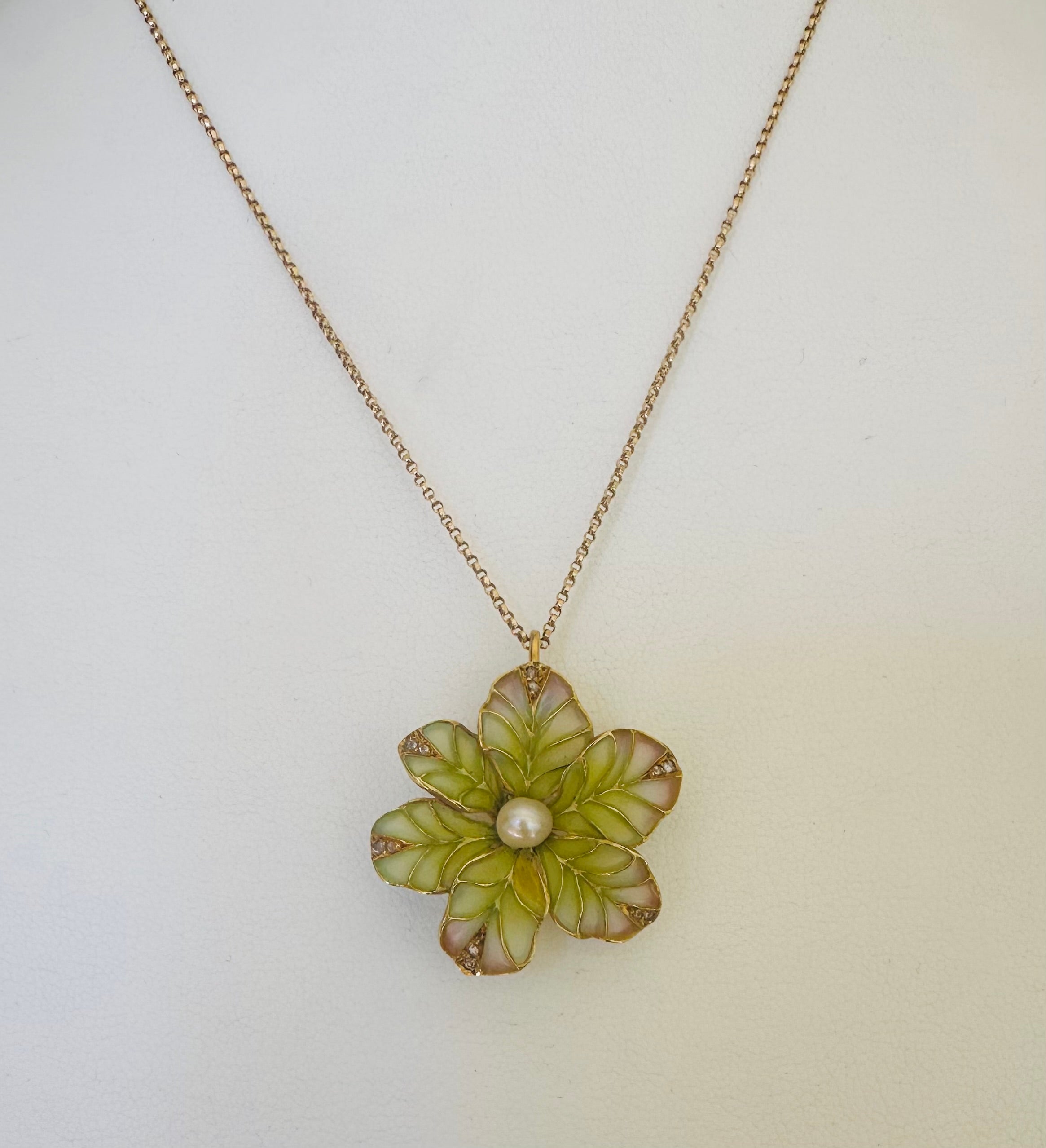 Una singola perla bianca naturale è al centro di questo ciondolo a forma di fiore in smalto plique-a-jour con sfumature traslucide di verde e rosa, che conferisce ai petali un'eccezionale luminosità.  Le punte dei petali sono impreziosite da due