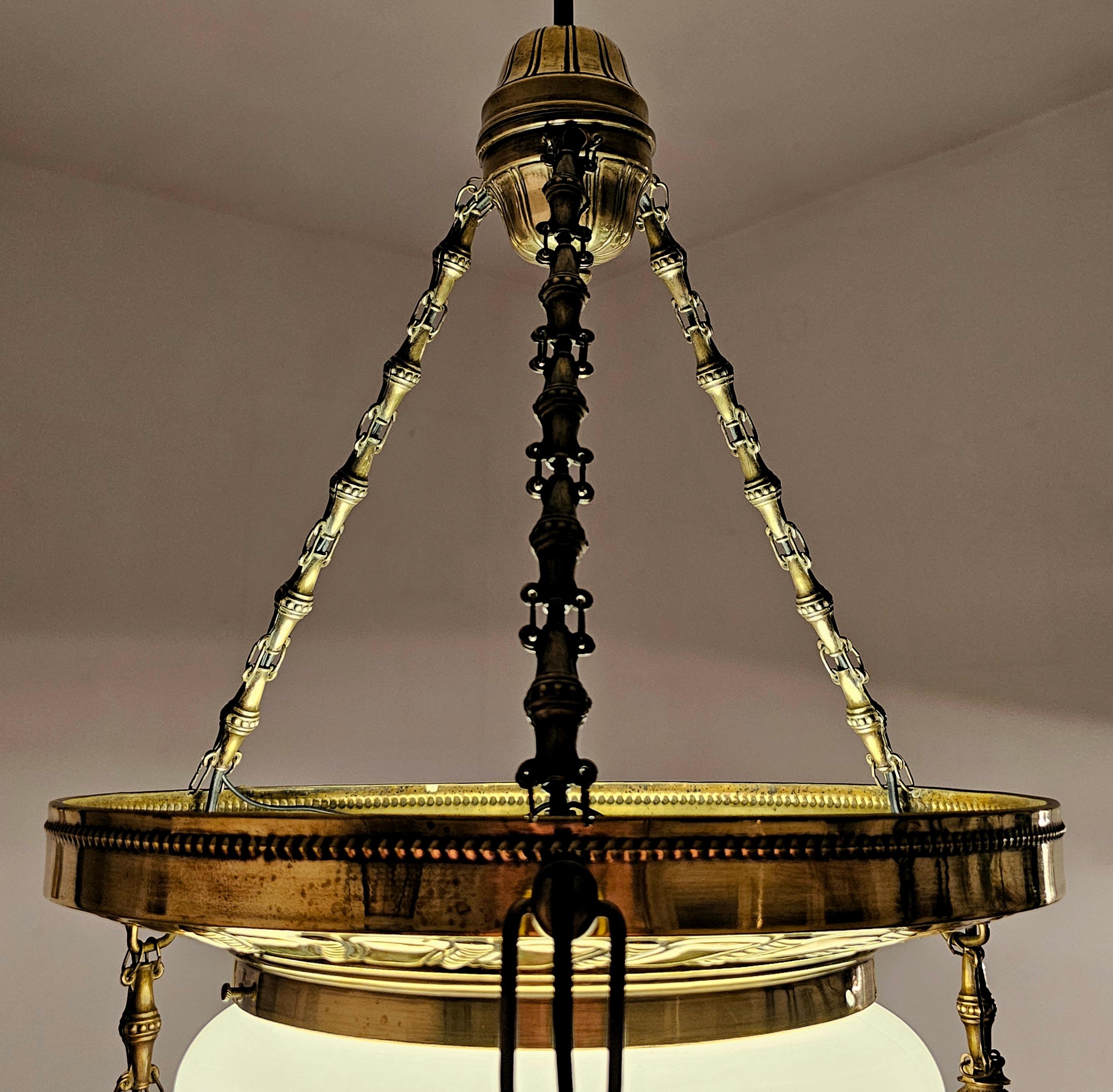 In this listing you will find a gorgeous Art Nouveau or Vienna Secession chandelier. It is done in polished brass with beautiful relief and the milk dome in the center. The chandelier features 4 lights, one based in the center underneath the milk