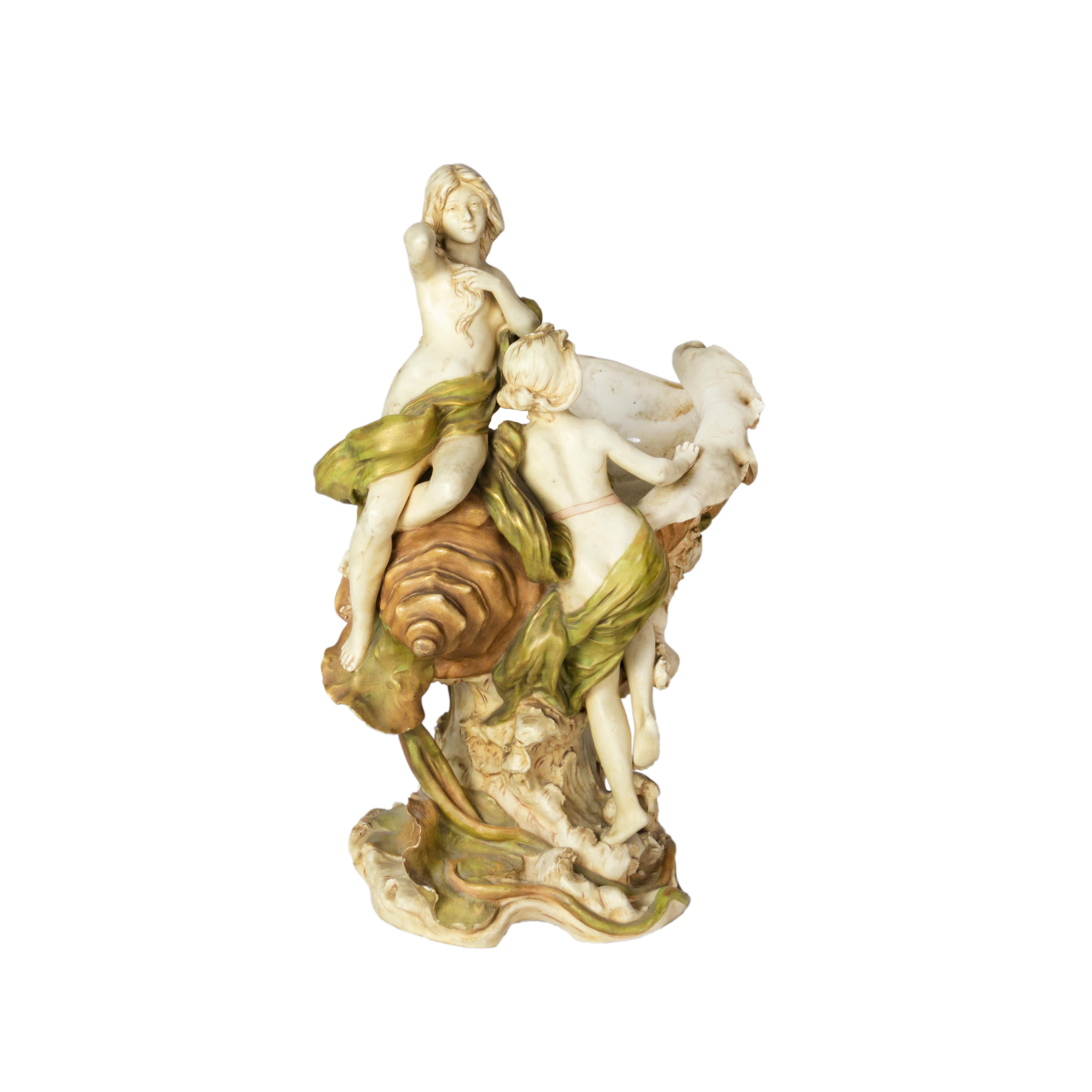 Centre de table en porcelaine Art Nouveau du début du 20e siècle, représentant deux jeunes filles nymphes émergeant d'un grand coquillage océanique. Cette pièce sculpturale est une célébration des formes naturelles et de la beauté féminine,