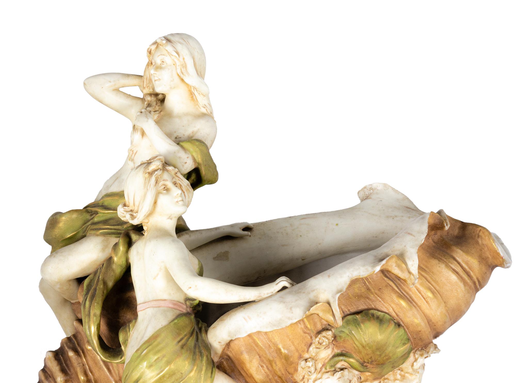 Un centrotavola in porcellana Art Nouveau dell'inizio del XX secolo, con due fanciulle ninfe che emergono da una grande conchiglia oceanica. Questo pezzo scultoreo è una celebrazione delle forme naturali e della bellezza femminile, magistralmente