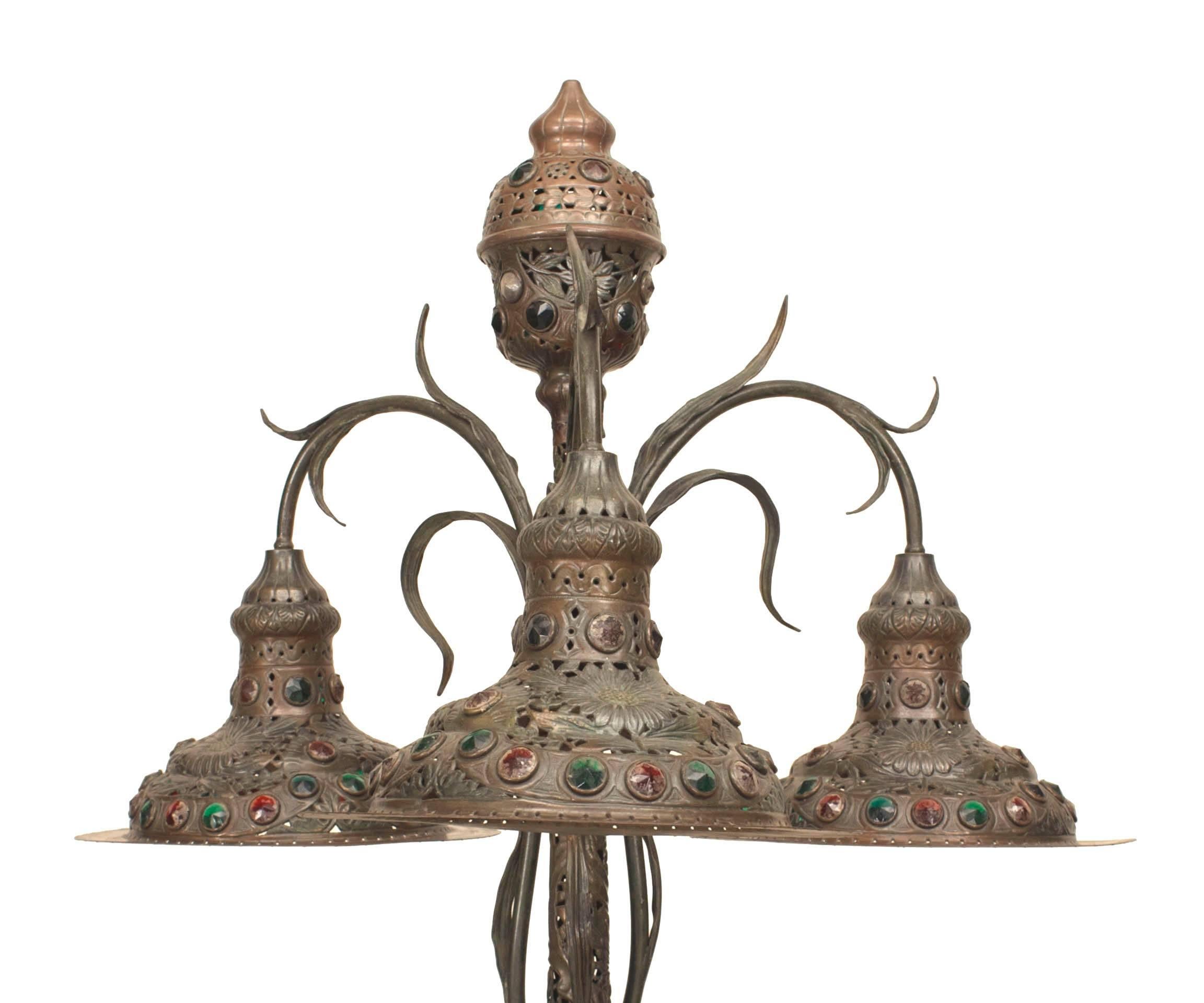 Lámpara de pie Art Nouveau (posiblemente húngara) con metal patinado en verde oscuro y un diseño de filigranas florales y enredaderas. Inserción de joyas de cristal y soporte de 3 pantallas redondas colgantes.
