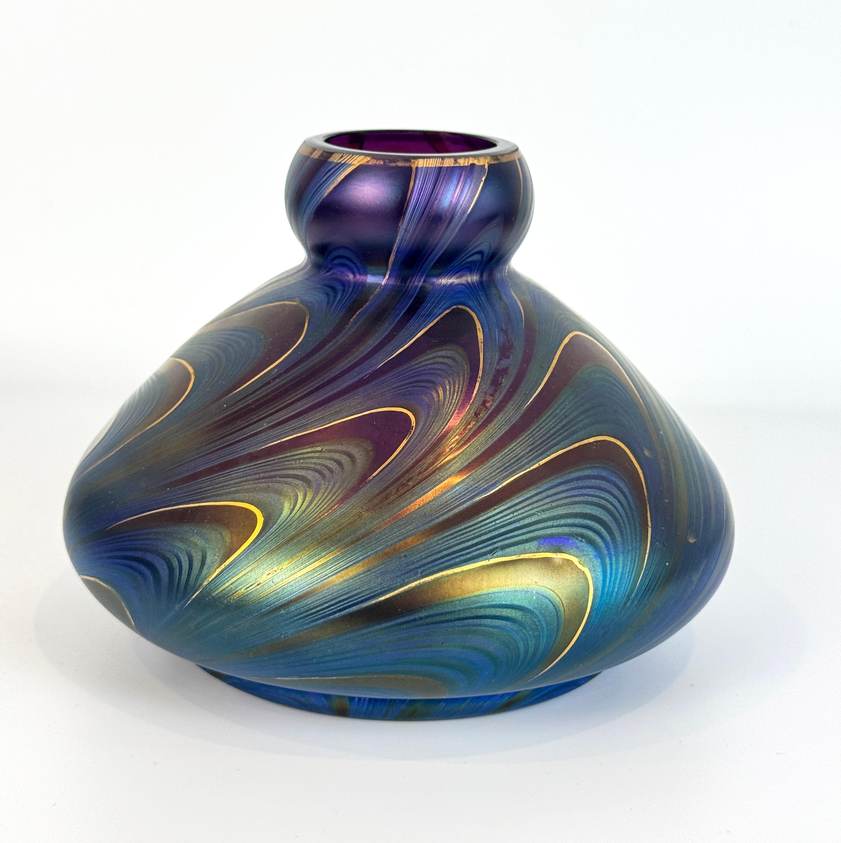 Un bellissimo vaso in vetro iridescente Art Nouveau nei colori blu, verde e ametista con decorazioni dorate a forma di piuma. Il vaso ha una forma deliziosa, l'altezza perfetta per una mensola o un tavolo decorato, ha una base ampia che si