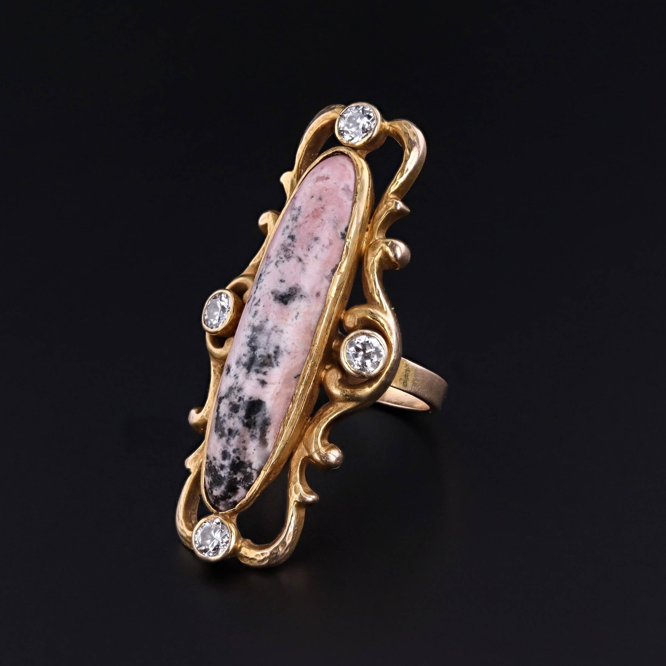 A striking jewel from the Art Nouveau era (circa 1890–1900), this antique ring makes a bold impression with its elongated design and distinctive color contrast. The centerpiece is a tall, polished pink and black rhodonite, prized for its natural