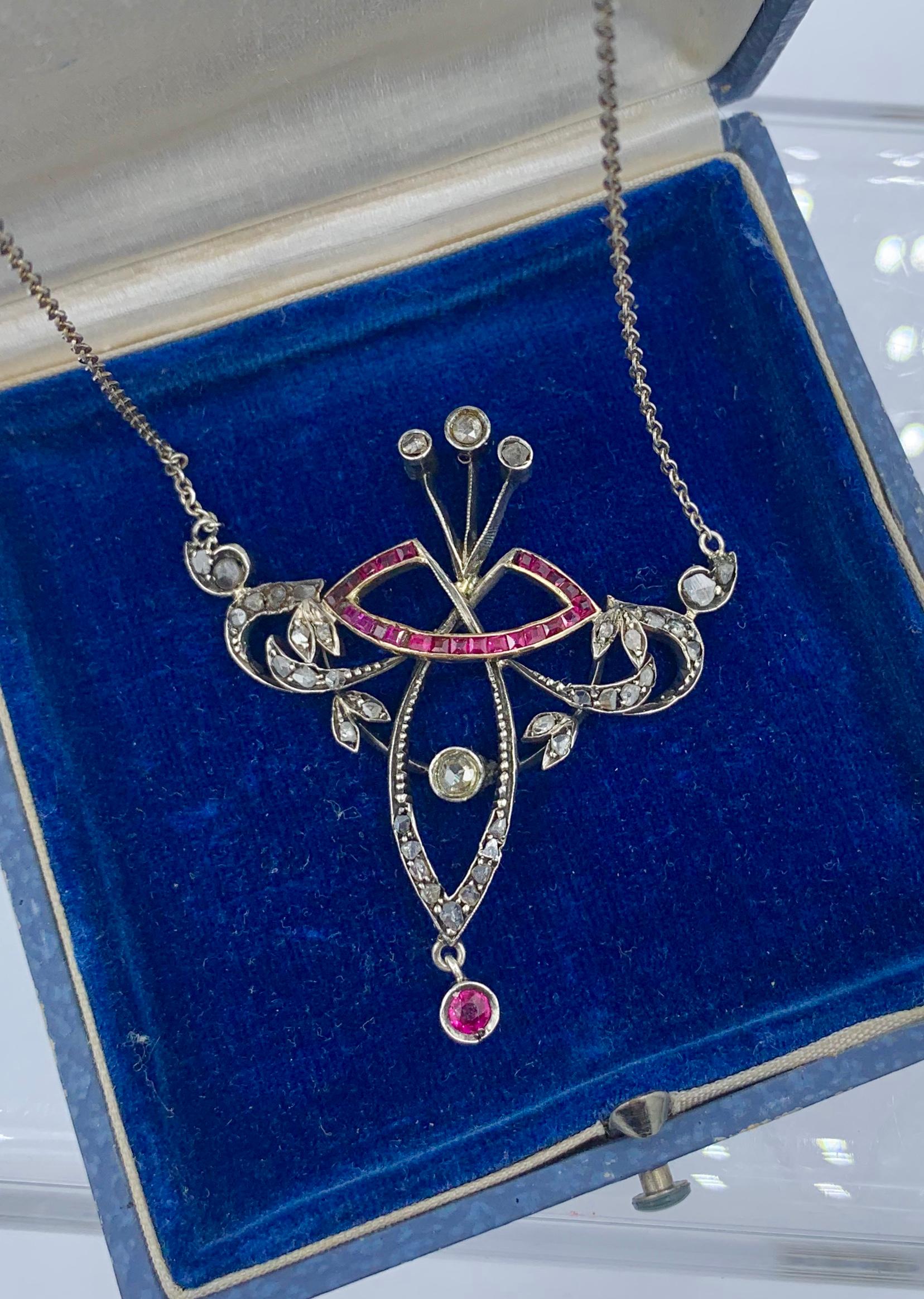 This is an extraordinary museum quality Art Nouveau, Belle Epoque Pendant Necklace set with Rose Cut Diamonds and channel set Rubies in a scroll motif open work crown design.  The jewels are set in 14 Karat Gold.   The Rose Cut Diamonds sparkle with