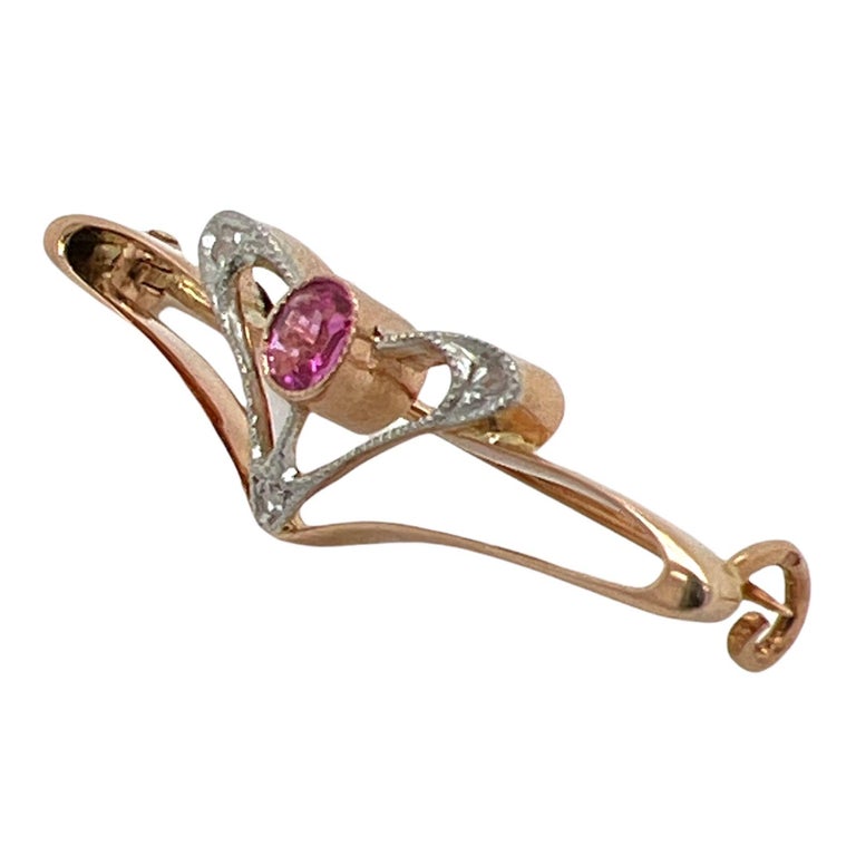 Beautiful original Art Nouveau ruby and diamond brooch handcrafted in 14 karat rose gold. The pin features an approximately .24 carat oval ruby gemstone and 3 rose cut diamond accents. The brooch measures 10 x 35mm. 