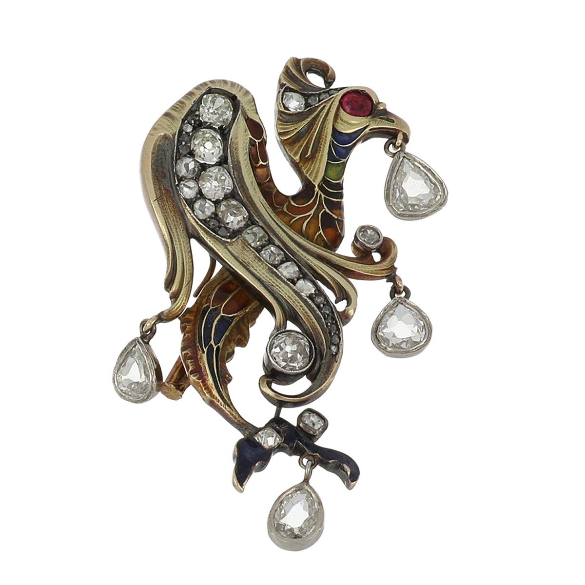 An Art Nouveau 14K yellow gold and sterling silver mythological creature (wyvern) brooch with multi-colored enamel, red spinel and diamonds. Russian, circa 1890. 

The wyvern is set with a cushion-cut red spinel for an eye and 32 old mine-cut