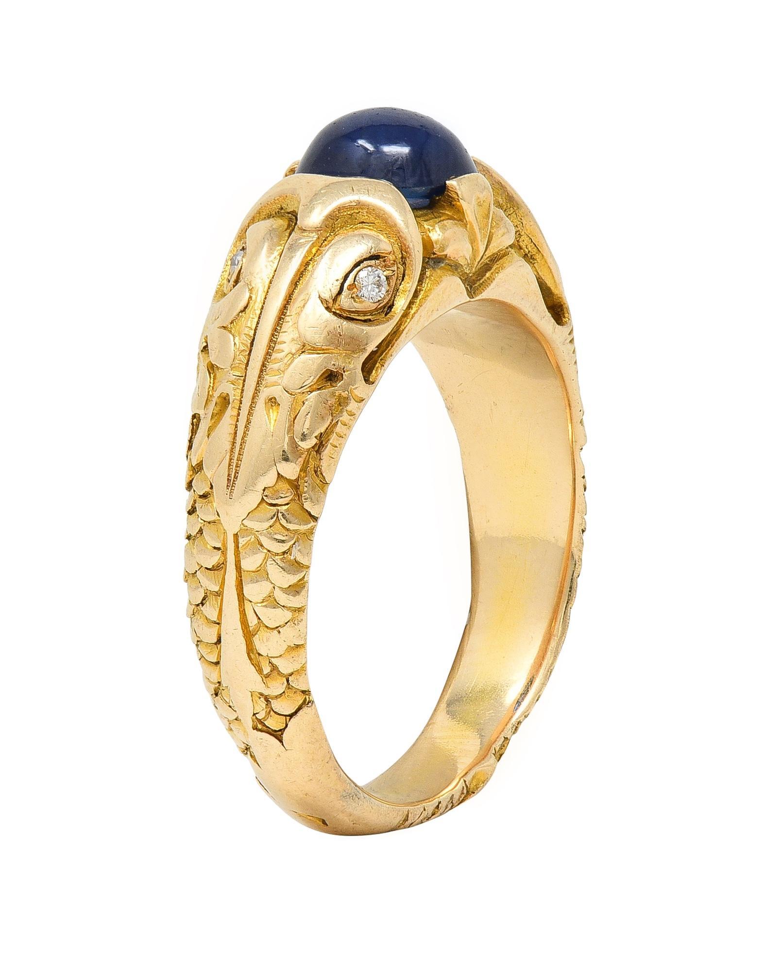 Centering an oval-shaped sapphire cabochon weighing approximately 1.61 carats total
Transparent medium blue in color and flush set in a highly rendered surround
Depicting two stylized koi fish shoulders with engraved features
With grooved texturous