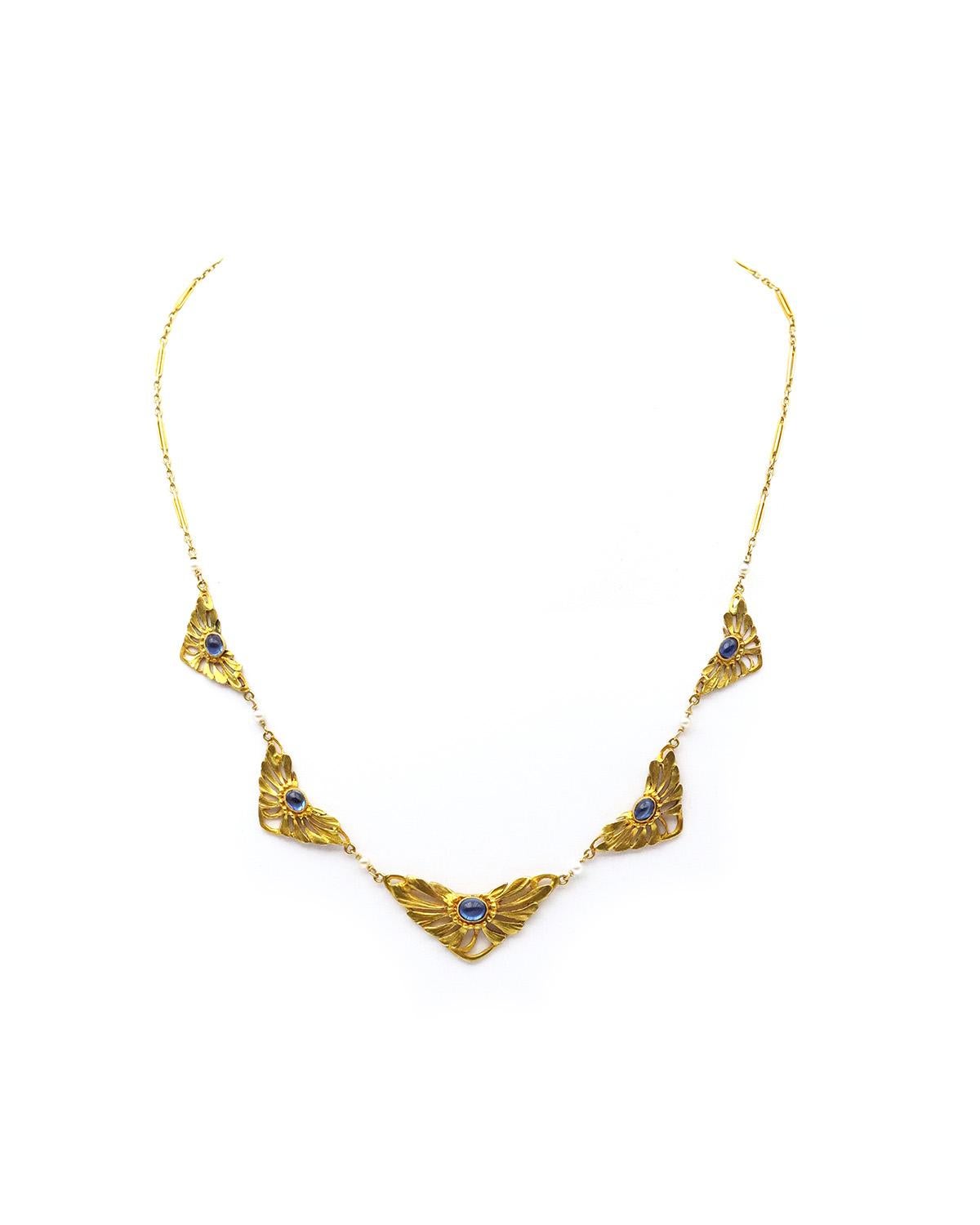 Collana di zaffiri Art Nouveau in oro 18 carati. La collana è composta da cinque piastre triangolari decorate con petali di margherita, ciascuna con uno zaffiro sintetico cabochon al centro. Le piastre sono alternate da sei perle sottili, ciascuna