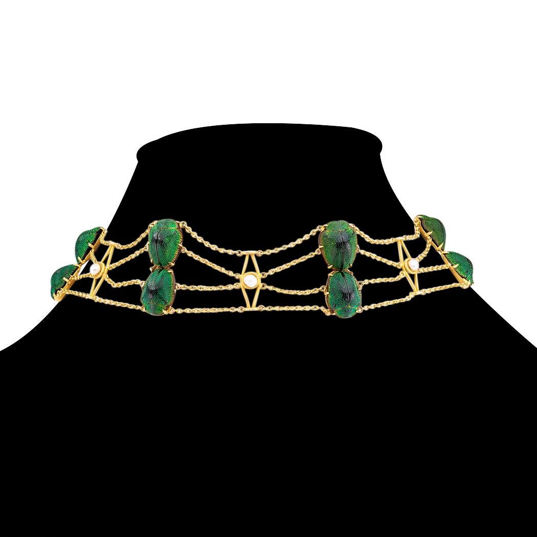 Art Nouveau scarab pearl and gold collar by Johnston circa 1905.

DETAILS:
MATERIALS:  gold backed iridescent green scarabs.

GEMSTONES:  pearls.

METAL:  14-karat yellow gold.

MEASUREMENTS:  approximately 1-1/16” (2.7 cm) wide and 14-1/2” (36.80