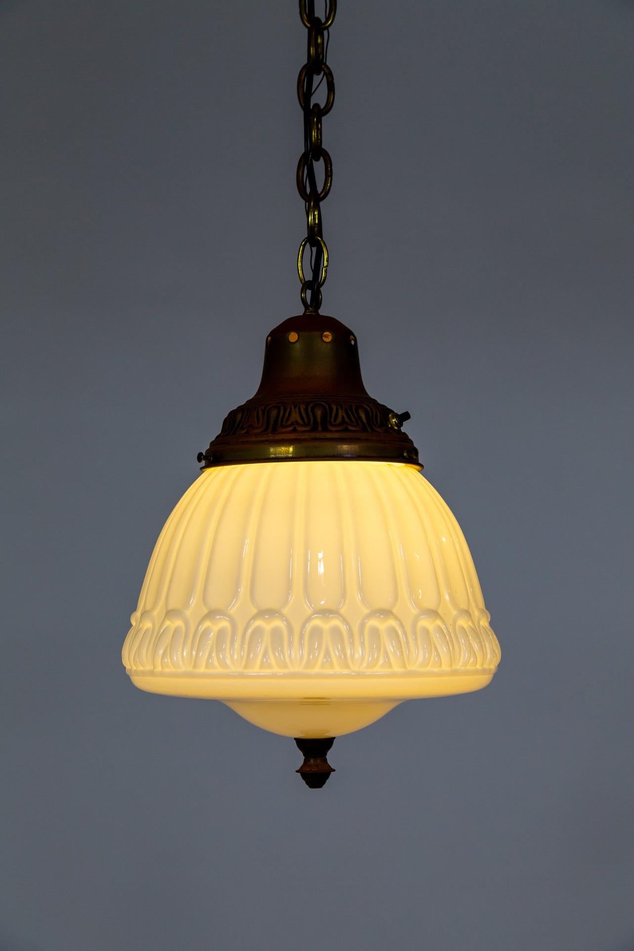 Un'incantevole lampada a sospensione in vetro risalente agli inizi del XX secolo. Il baldacchino e il portabicchieri in ottone hanno una finitura ramata e sono accentuati da un terminale inferiore. Il vetro lattiginoso è modellato con un motivo a