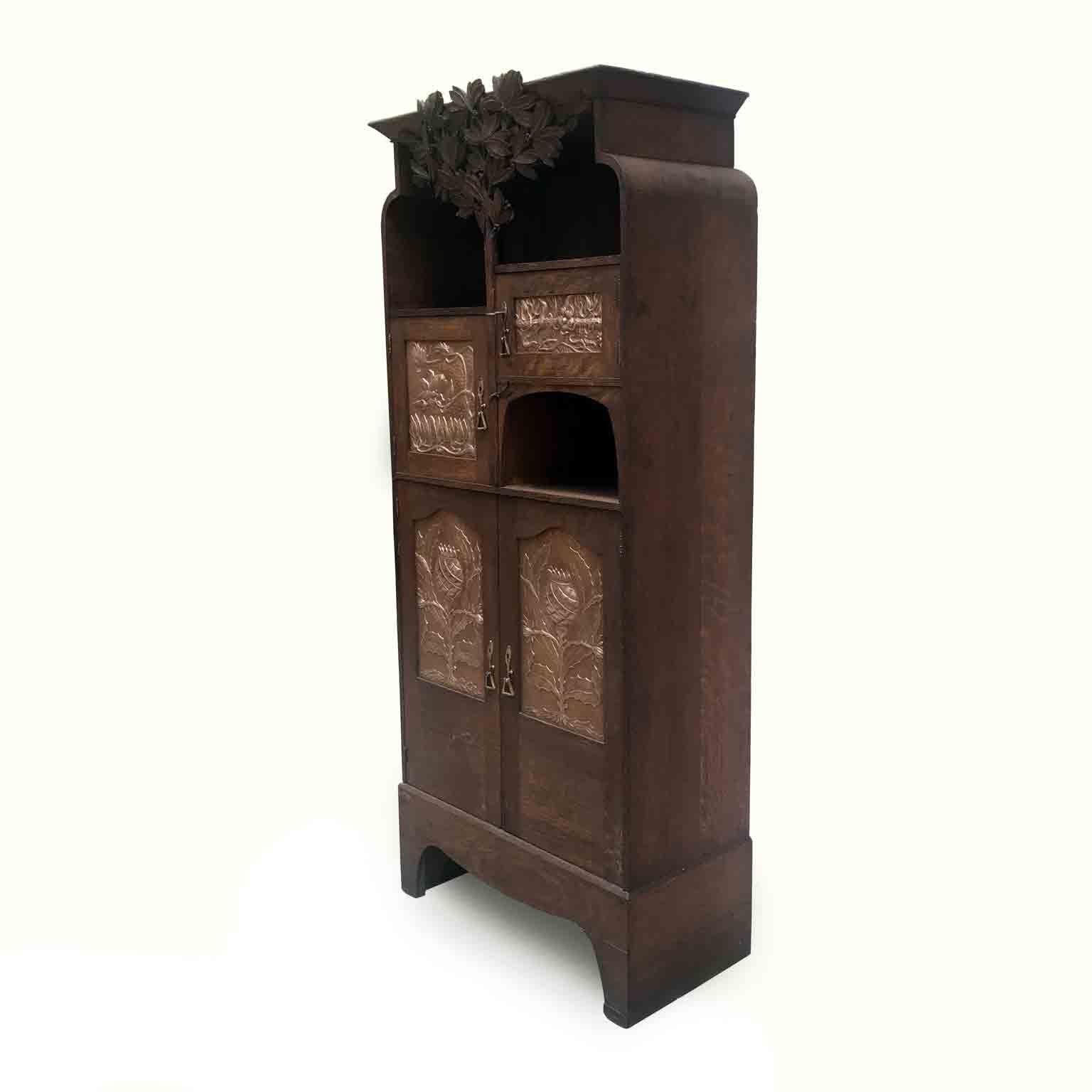 Lovely Art Nouveau small cabinet, a solid carved oak Scottish furniture, with four doors and three asymmetric pigeon holes, circa 1910. Nature inspires the decoration of this antique cabinet, in the style of Glasgow school and the manner of Charles