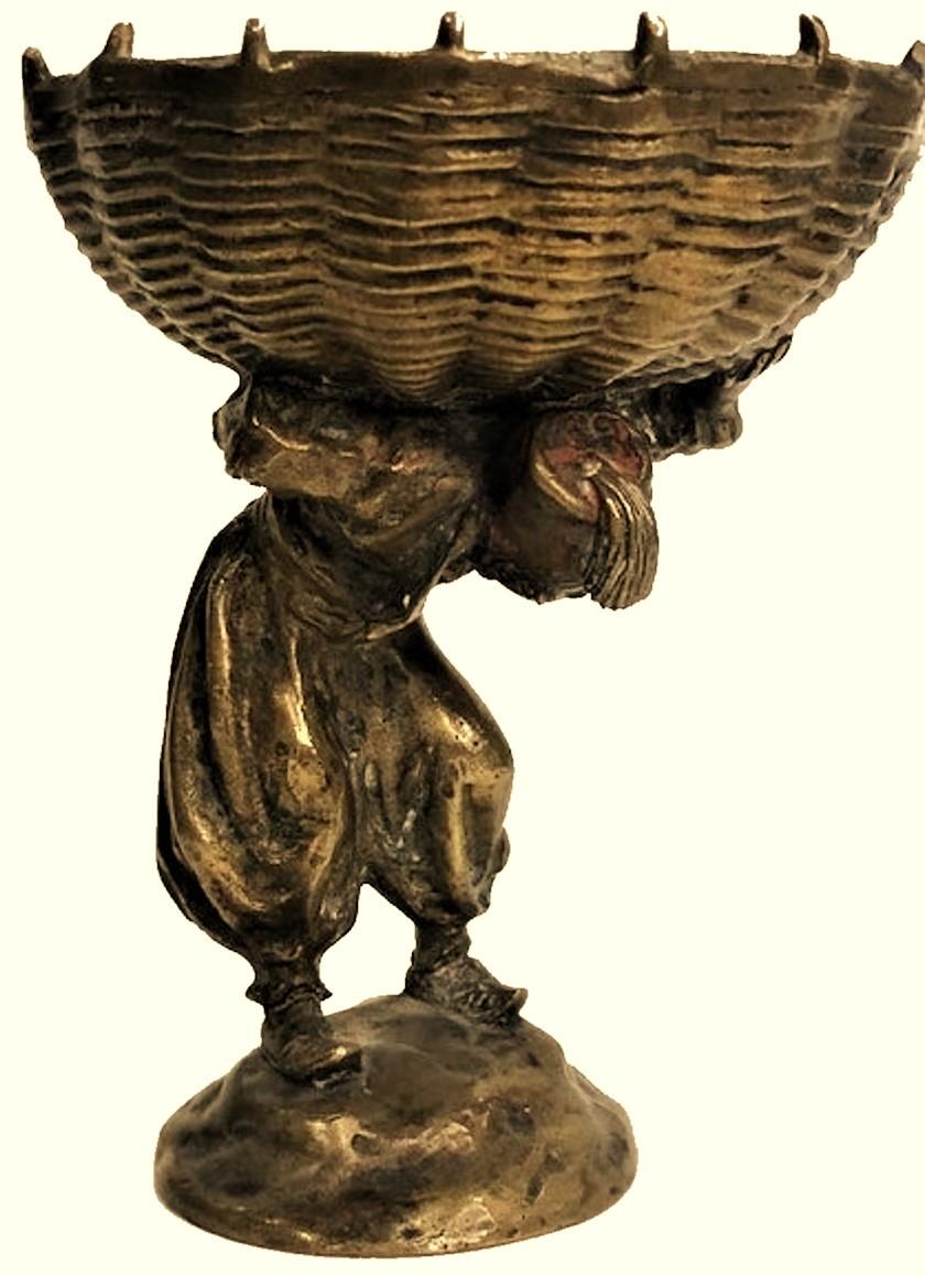 Probably, Austrian, this very original Art Nouveau orientalist sculptural candy bowl made of gilded Viennese bronze, depicts a young street vendor in bloomers and a fez, holding a huge round straw woven basket on his shoulders.
