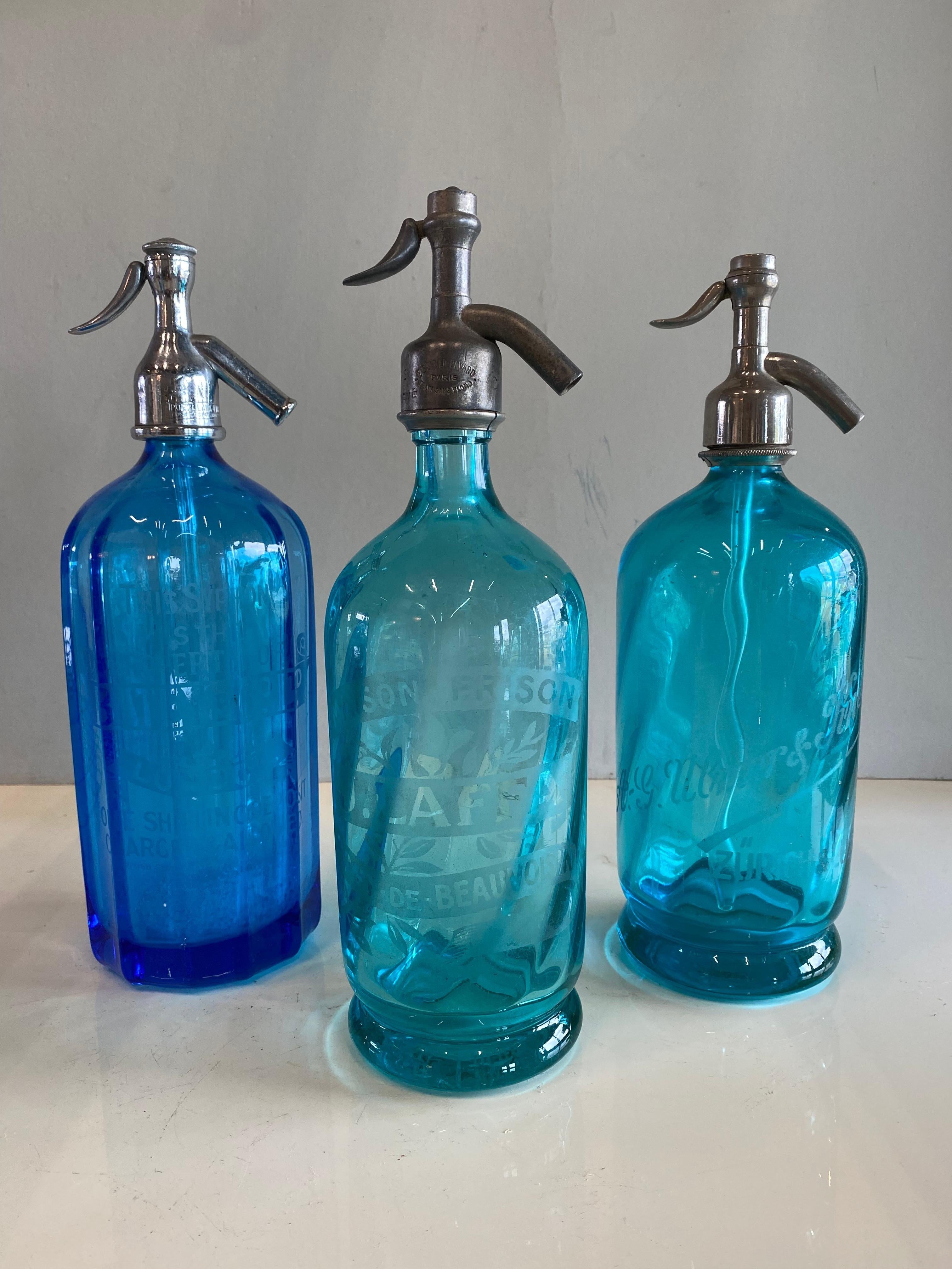 Antike Siphons aus Frankreich aus den Jahren um 1900. Die Flaschen sind aus dickem, schwerem blauen und türkisfarbenen Glas und die Verschlüsse aus Zinn gefertigt. 
Auf dem Deckel der blauen Flasche sind das Wort und die Zahlenfolge 