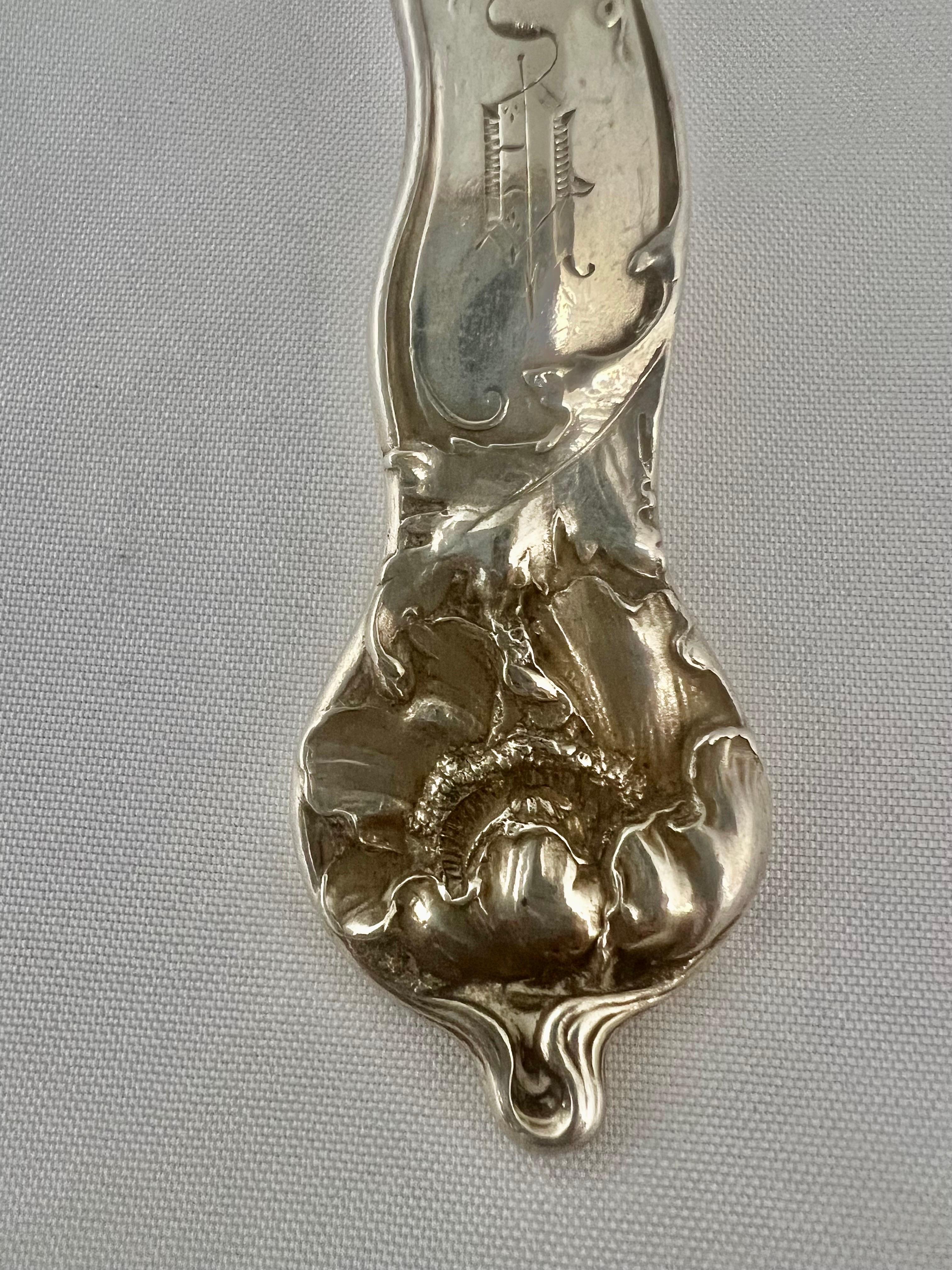 A sterling silver Art Nouveau Serving Spoon by George W. Shiebler & Company.  This piece showcases the distinctive and flowing lines characteristic of the Art Nouveau style.  Pieces from this era often feature nature-inspired motifs and intricate