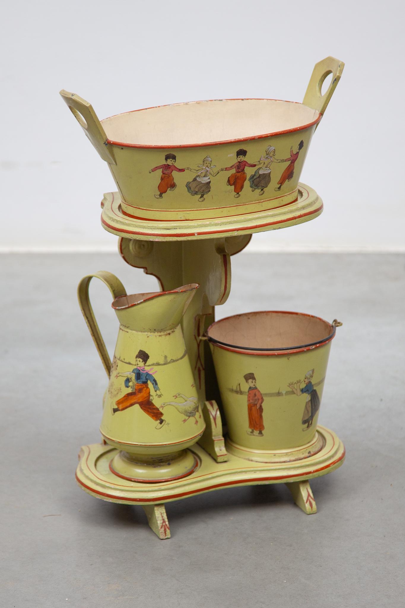 Ensemble de 3 pièces décorées Art Nouveau : un seau à linge, une cuvette et un seau sur un présentoir en bois. Peint en vert tendre avec des enfants et des animaux qui dansent.
Des jouets pour enfants copiés sur le monde du travail des adultes. Un