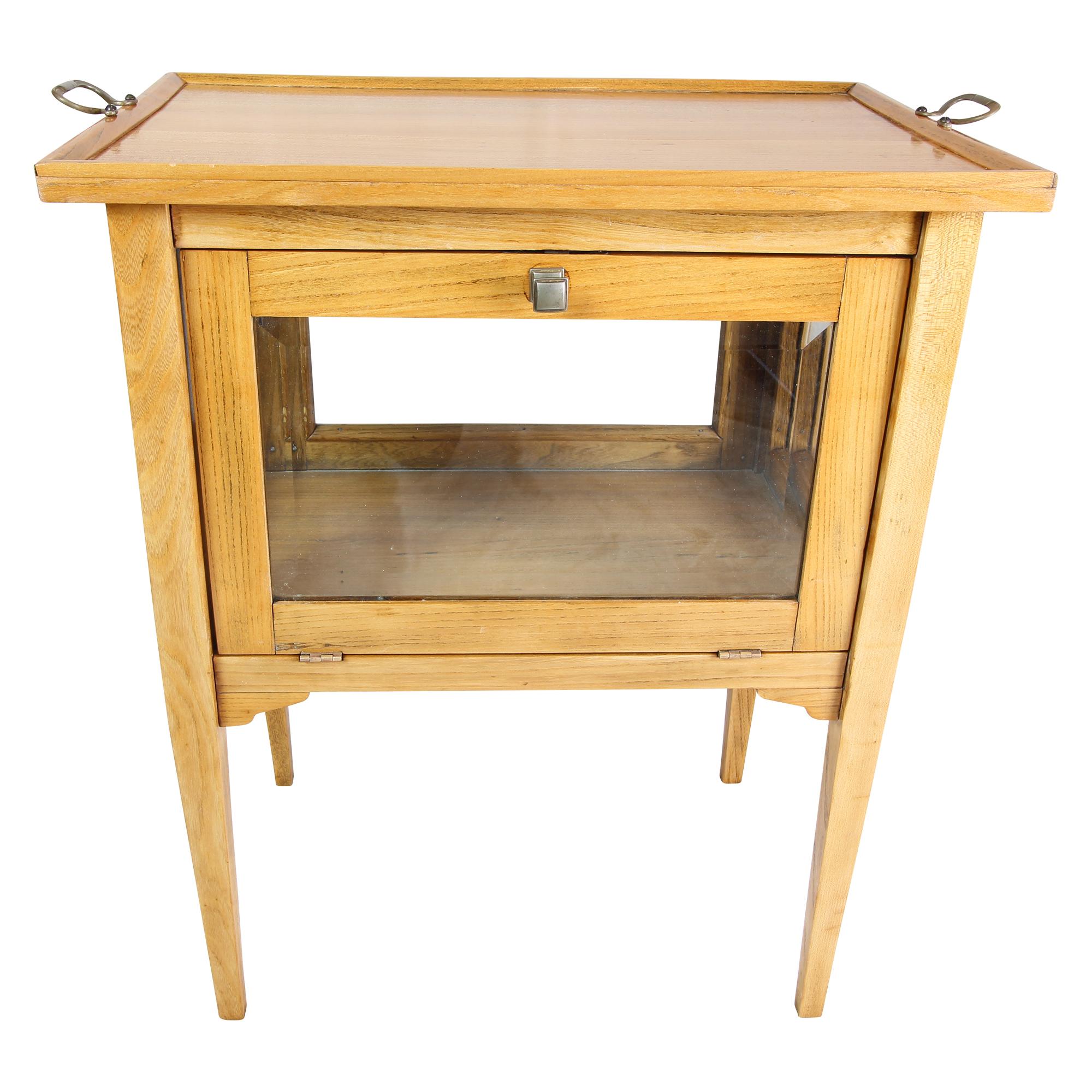 Beautiful small showcase table from the Art Nouveau period made of ash and oak wood. On all four sides are installed glasses with circumferential facet cut. A wide side can be opened via a snap lock and 180 ° down. The top is fixed and has two brass