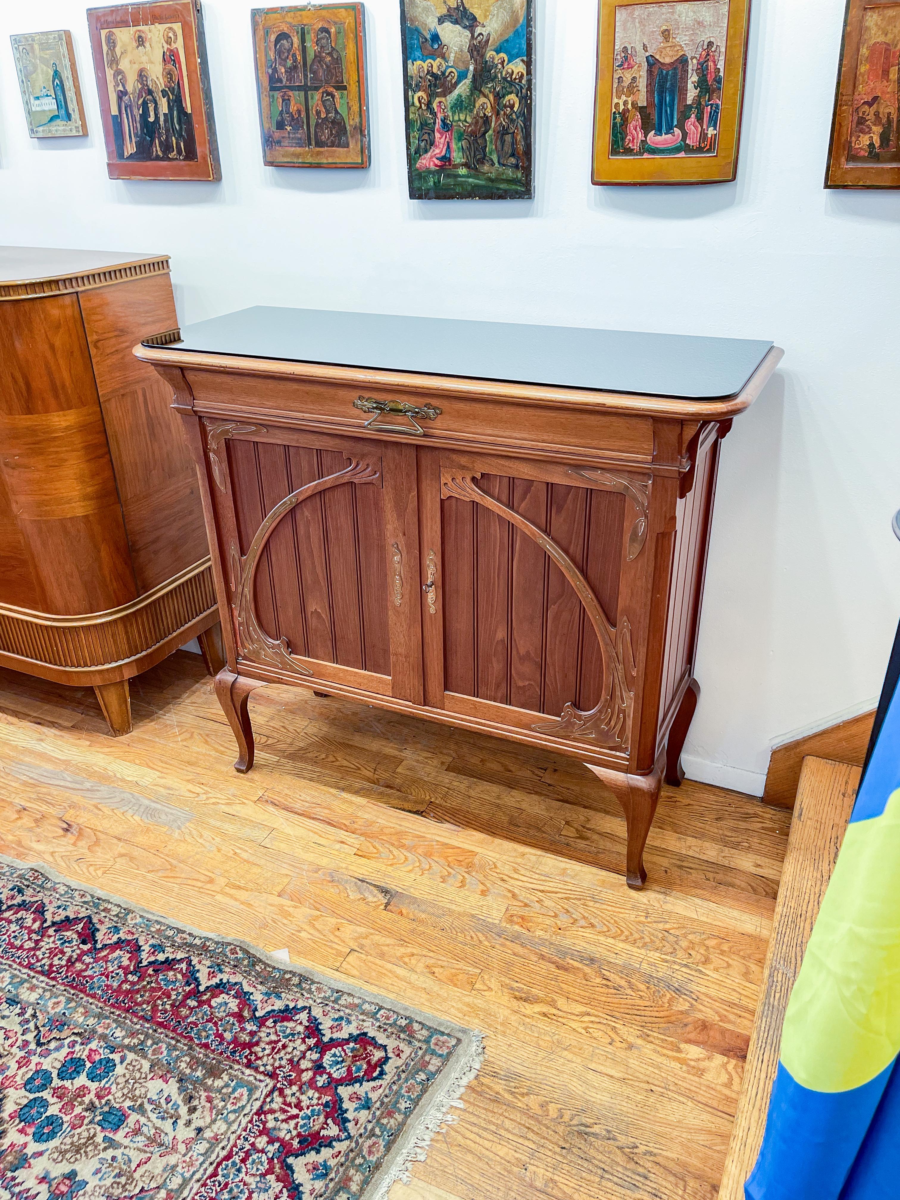 A beautiful and fully solid sideboard. Brass Hardware and appliques complement the swooping art nouveau case. The case is constructed of solid frames inset with floating mahogany boards.  

The frame of the case is solid, and curves according to the