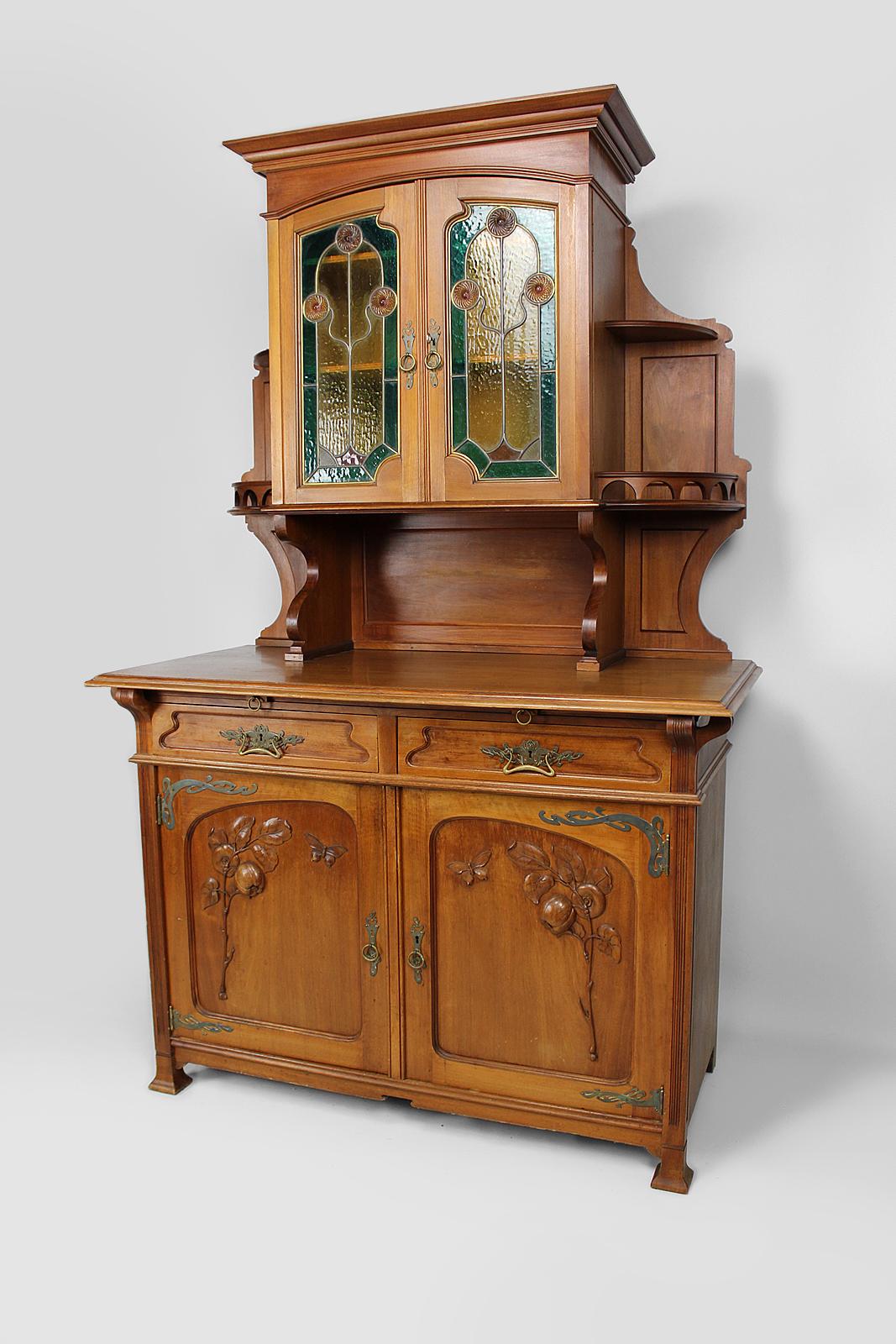 Superb buffet two bodies / dresser / sideboard in mahogany on a naturalist theme: butterflies, fruits (quinces).
There are magnificent brass ornaments as well as stained glass with geometric patterns at the doors of the upper part.
The lower part