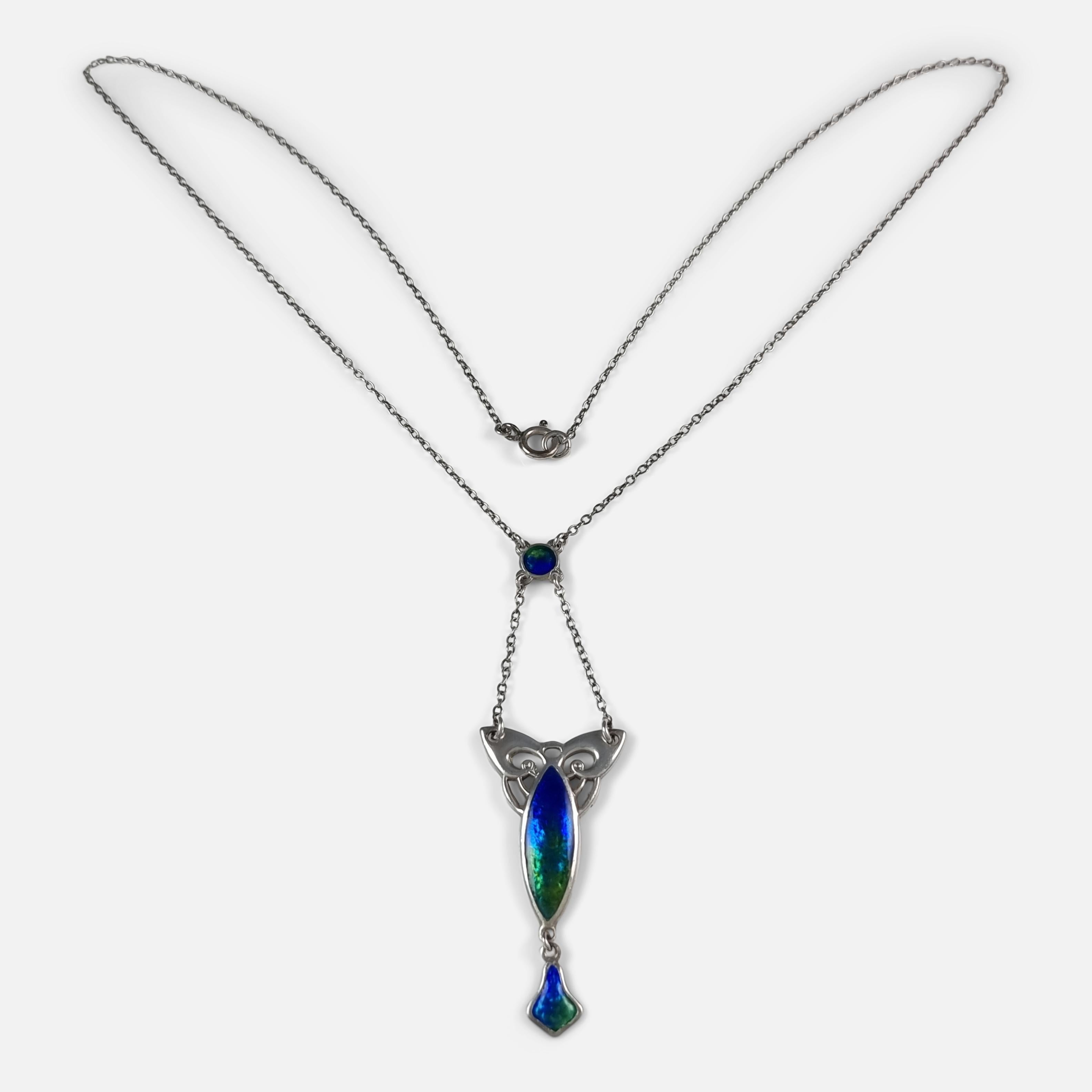 An Art Nouveau sterling silver and enamel pendant necklace by Charles Horner. The open-work pendant is enameled in shades of blue and green, leading to a further enameled drop. The pendant is connected by two trace link chains to an enameled