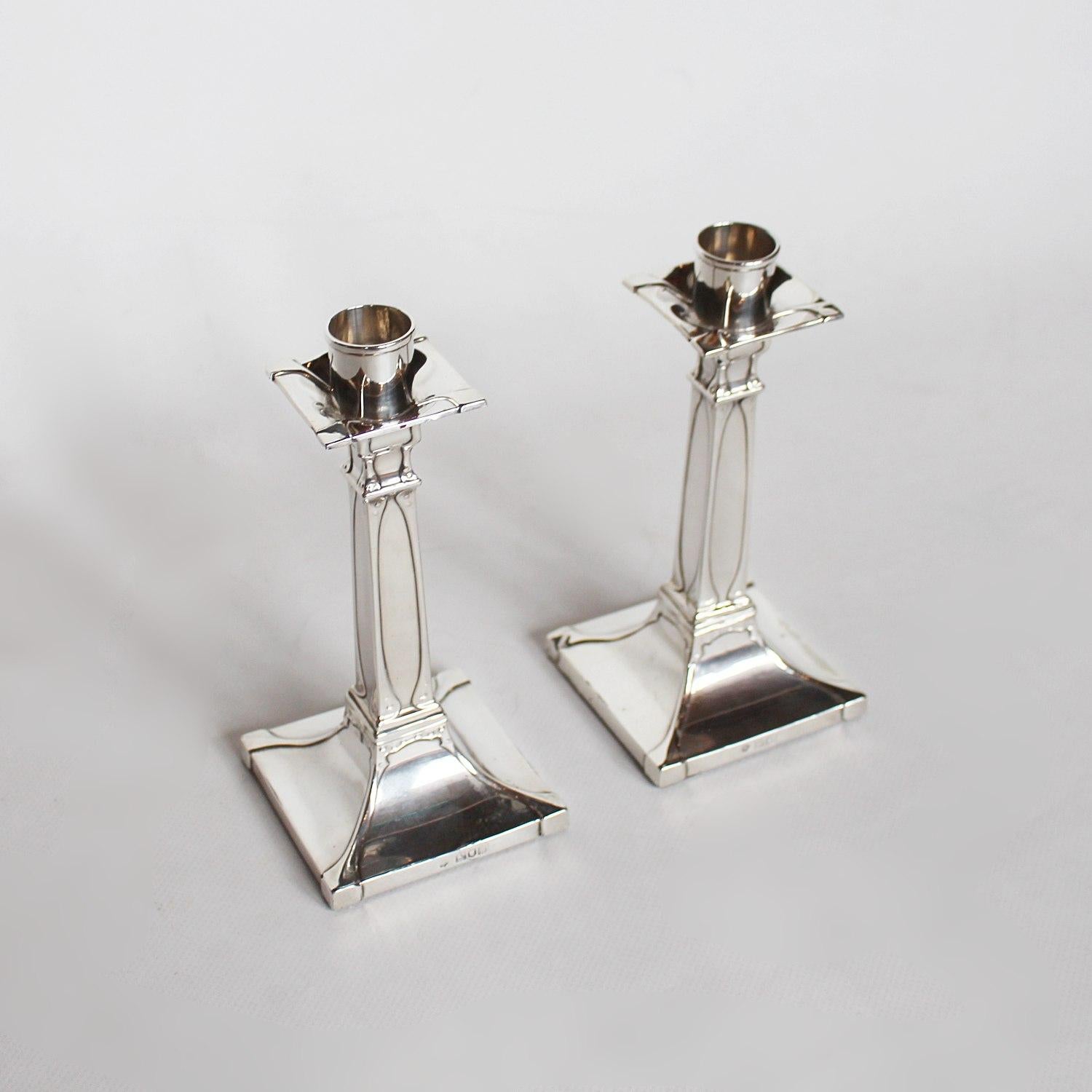 A pair of Art Nouveau silver candlesticks with tapering square stems. 

Maker: William Hutton & Sons Ltd

Date: dated London, 1909.
 