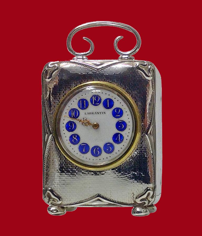 Antique silver carriage clock, Birmingham 1911, ? & Co. The clock on four bun feet with hinged plain scroll design handle, the front, lightly engraved wriggle work checkered design, Art Nouveau border with circular white enamel dial, royal blue