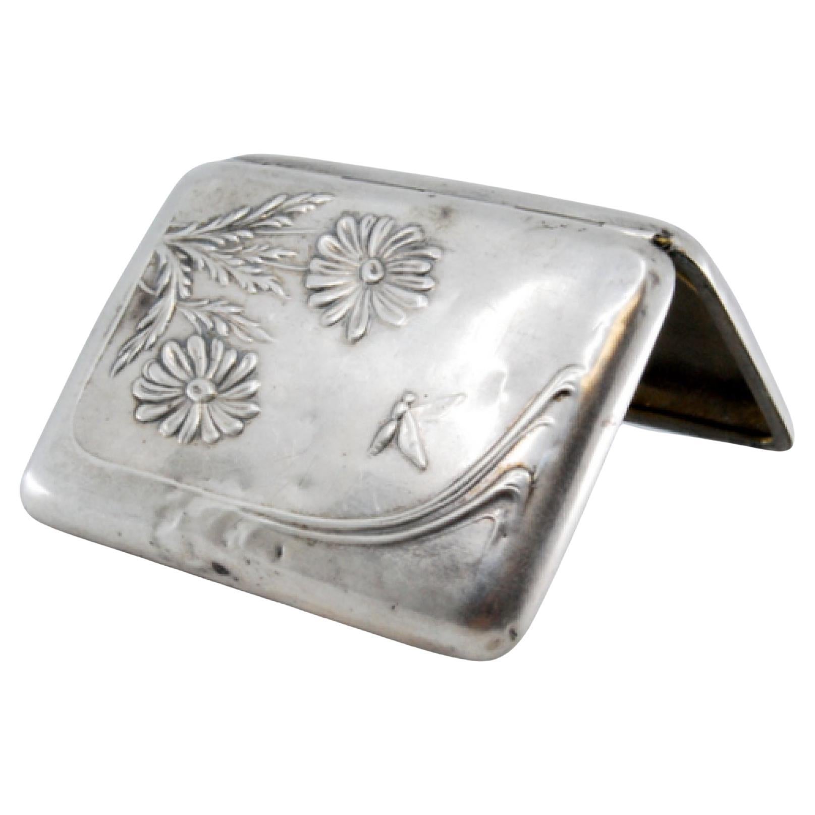 Descrizione: Portasigarette in argento in stile Art Nouveau con motivi floreali in rilievo e coperchio a cerniera. Metallo: Argento. Origine: Portoghese. Marchio: javali II Titolo. Peso: 54,43 grammi. Dimensioni: 8,1x1,4 cm. Marchio di controllo: