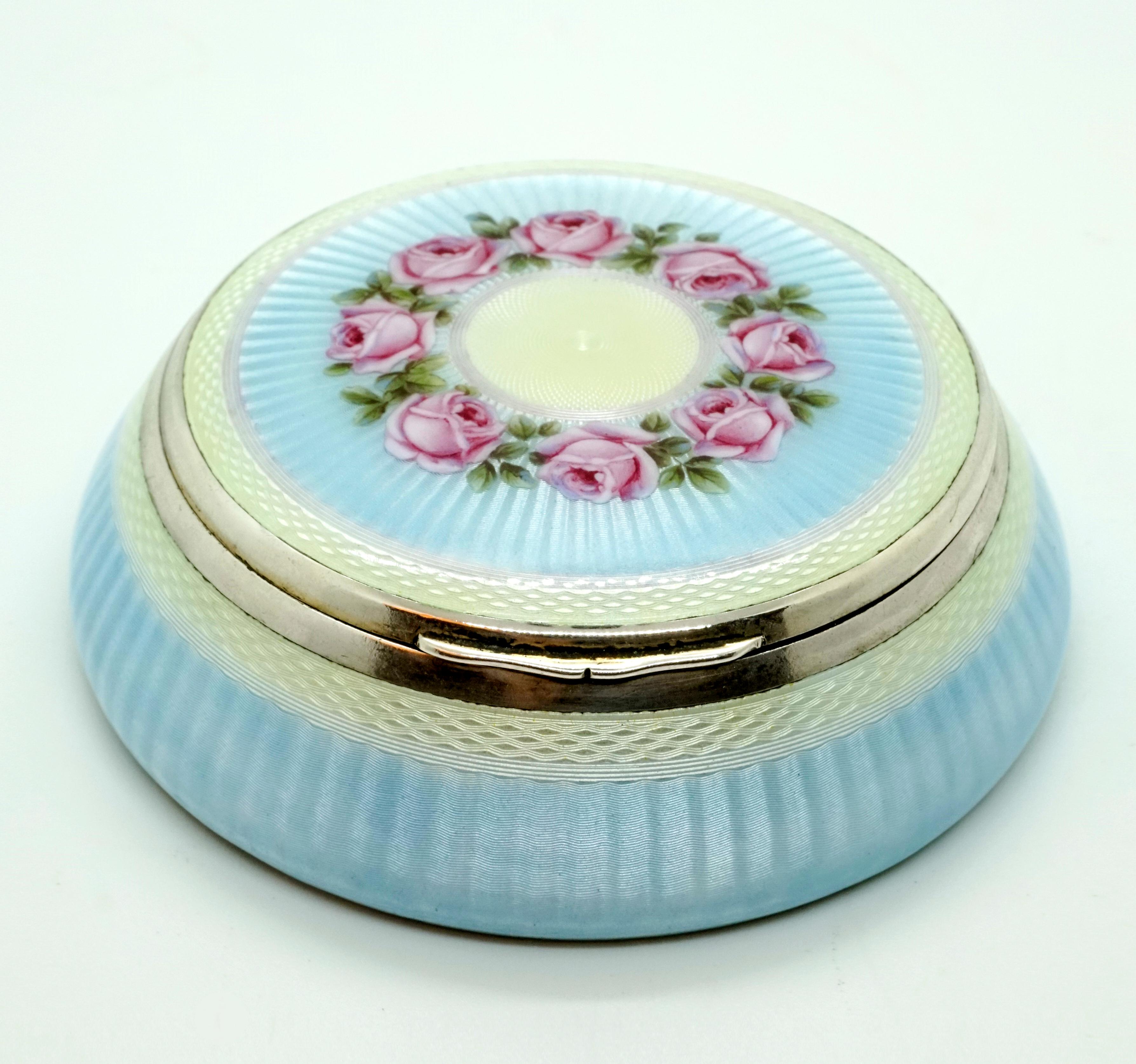 Exquisite enamel box from the period, circa 1900

Round silver box, completely gouilloché and enameled in light blue and cream white. Finest magnifying glass enamel painting, wreath with rose petals on the lid. Internal