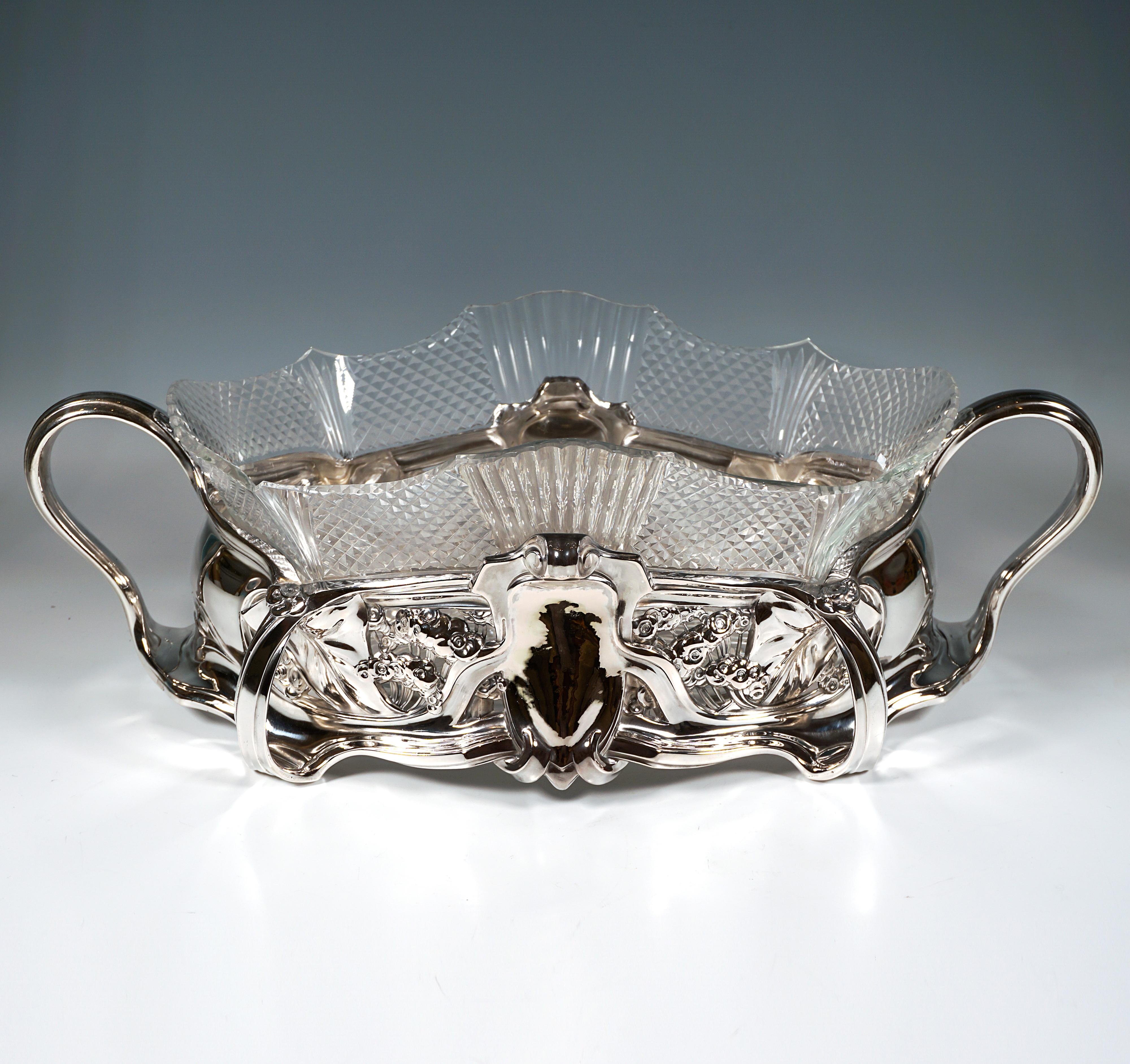 Elegantes, festliches Silbergefäß mit breitem, ovalem, naturalistisch gewölbtem Korpus, der untere Teil geschwungen und überlappend, mit vier vorspringenden Stäben, die Füße bilden, die auf dem Sockel ruhen und sich am oberen Rand wieder verbinden,