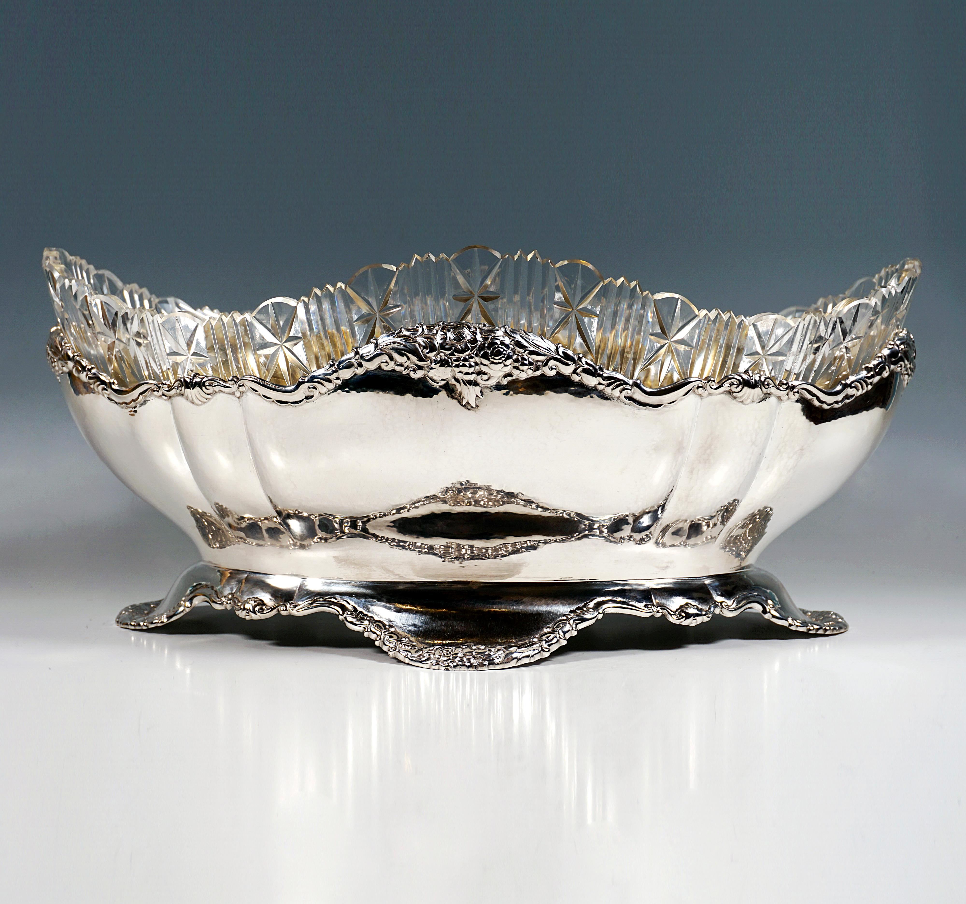 Festive solid silver vessel in the shape of a large oval footed bowl, divided and segmented by vertical folds, the base set off by a constriction, projecting, wavy, lobed cut-out foot, the upper edge of the bowl correspondingly wavy with the edge of