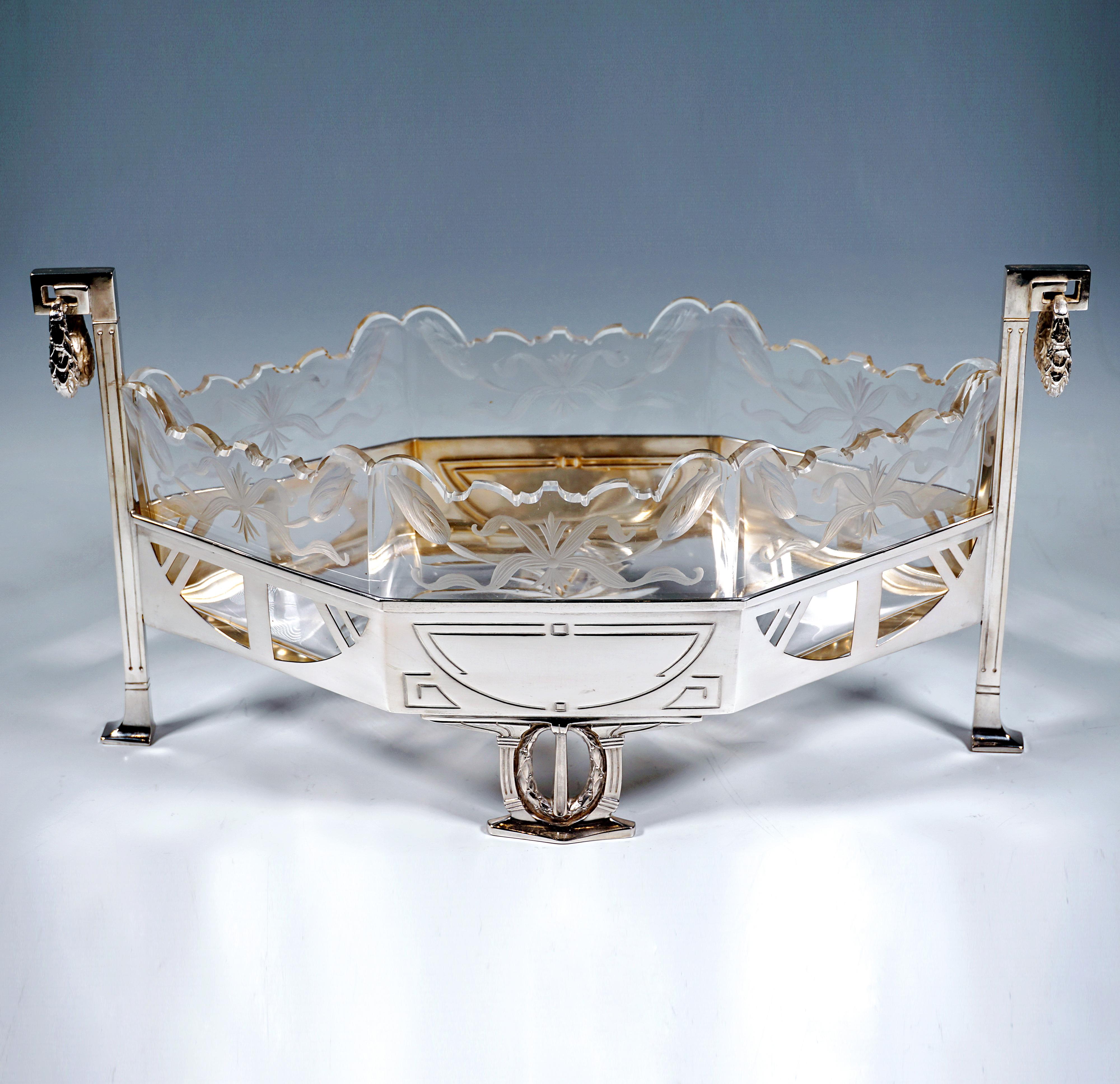 Elegante jardinera de plata de estricto estilo arquitectónico Art Nouveau, forma básica alargada en forma de panal, sostenida por dos montantes perfilados en las esquinas, que elevan mucho la pared en altura, y dos elementos de soporte más anchos en