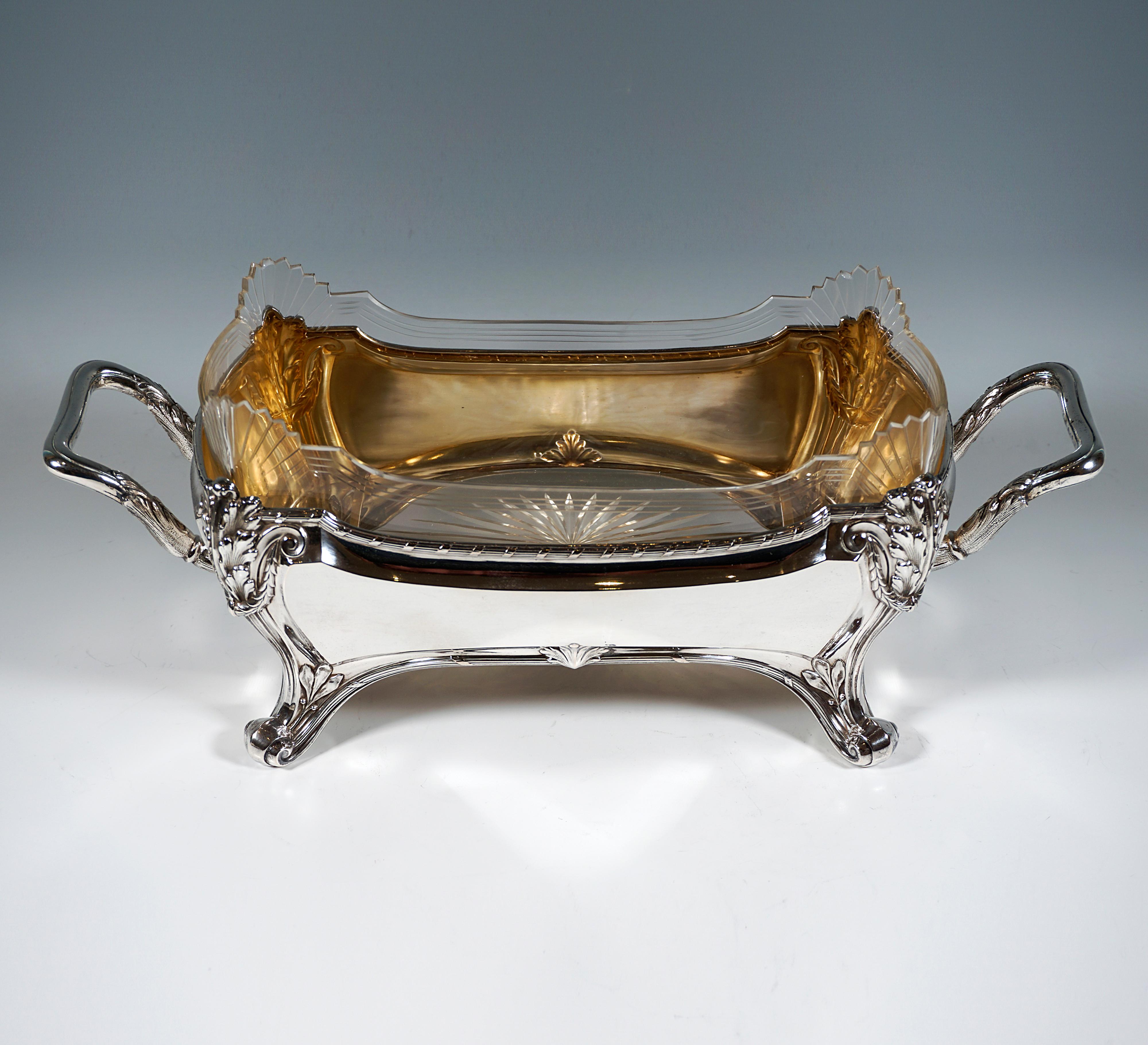 Elegant silver vessel in rectangular base form with slightly bulging side walls widening upwards, corner decorations with volutes and acanthus motifs in fluted pilasters tapering downwards to high volute feet, bundled decorative bands on top and
