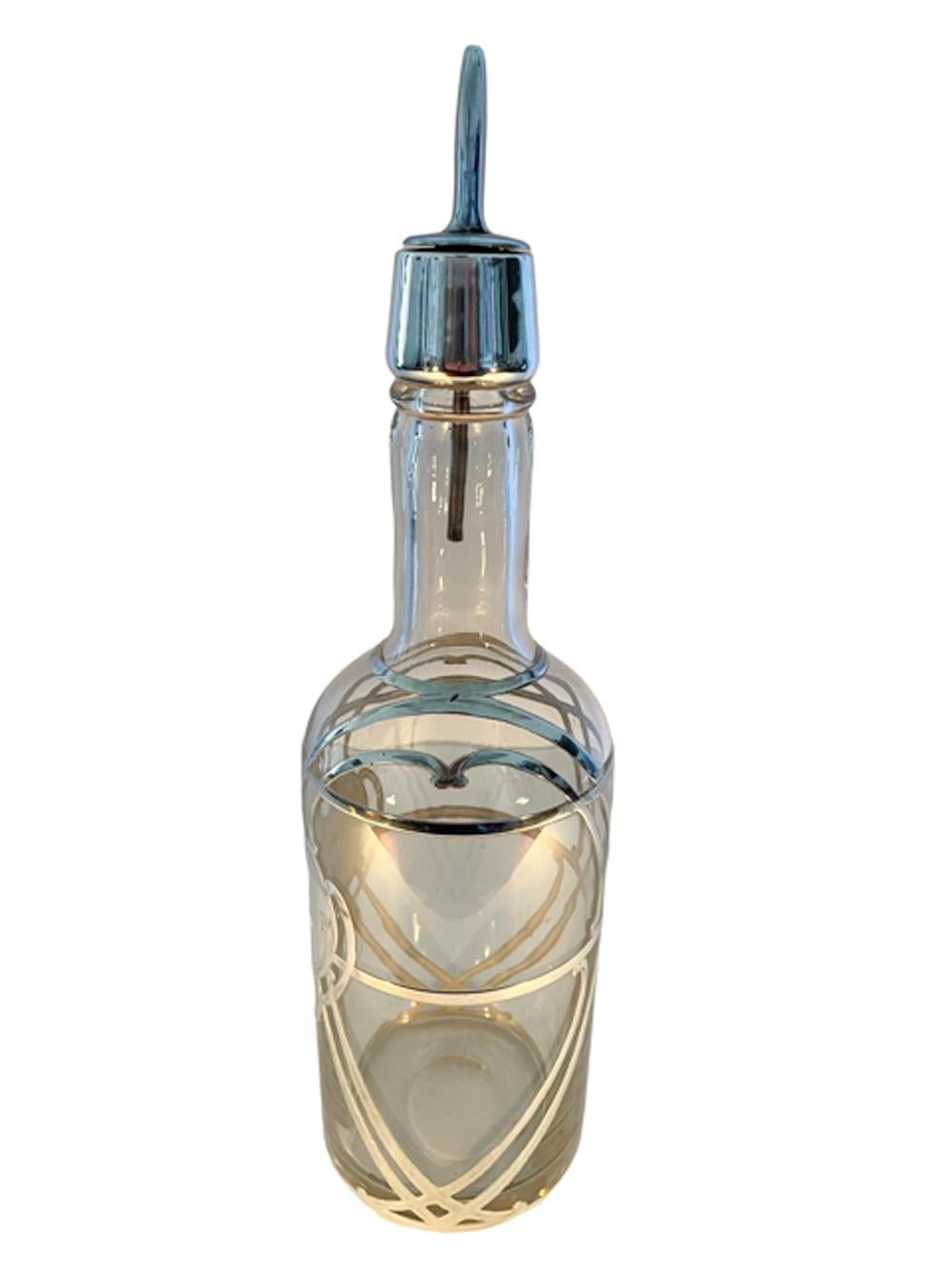 A silver overlay decanter or back bar bottle in clear glass with a polished pontil having a silver overlaid collar and large monogrammed central shield shaped cartouche with strapwork continuing around the bottle and over the shoulder. The bottle is