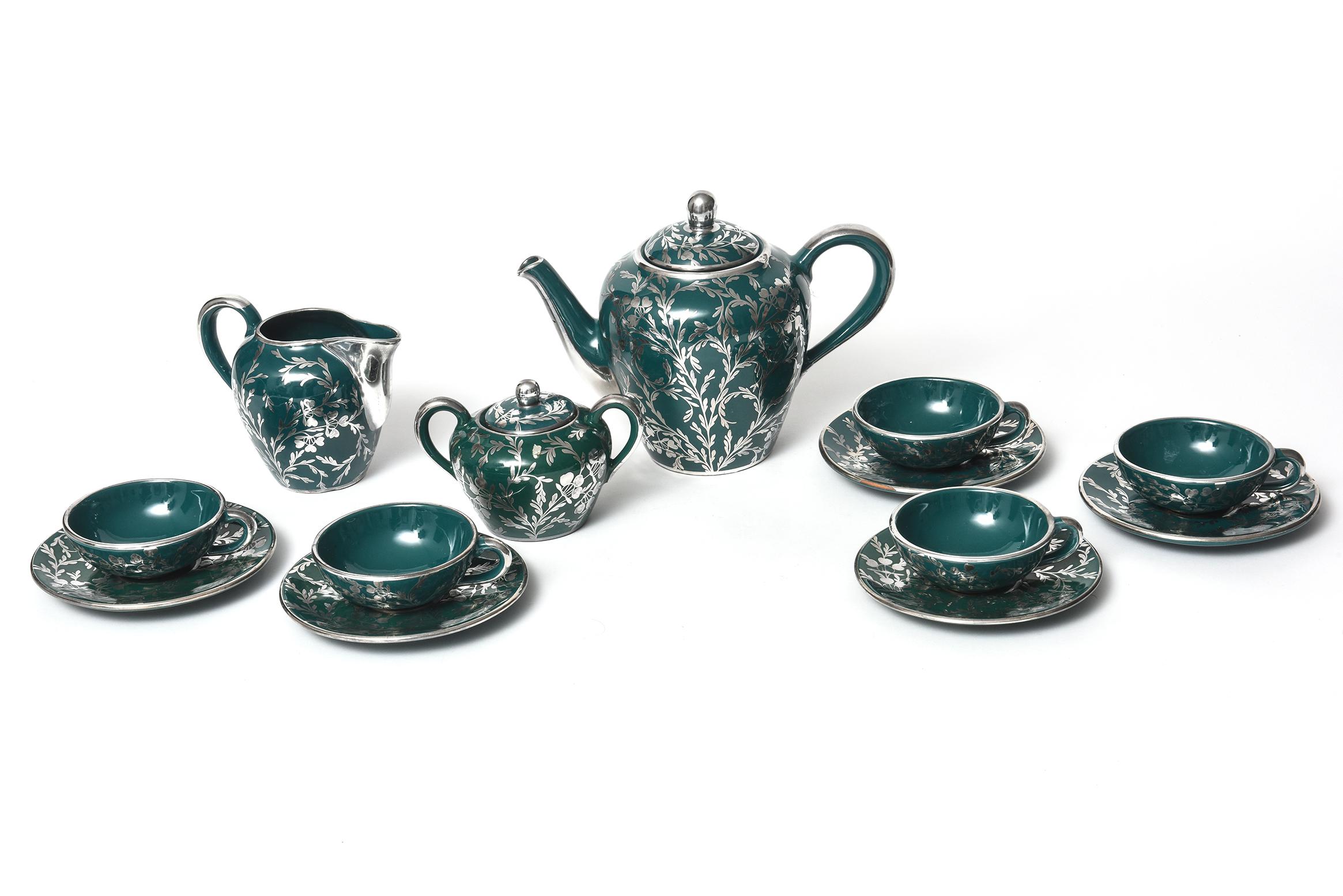 Beautiful antique art nouveau silver overlay green tea set featuring a silver scroll and floral/leaf design on green porcelain. The service for five includes a lidded tea pot, covered sugar bowl, creamer, five tea cups, and five saucers. There are