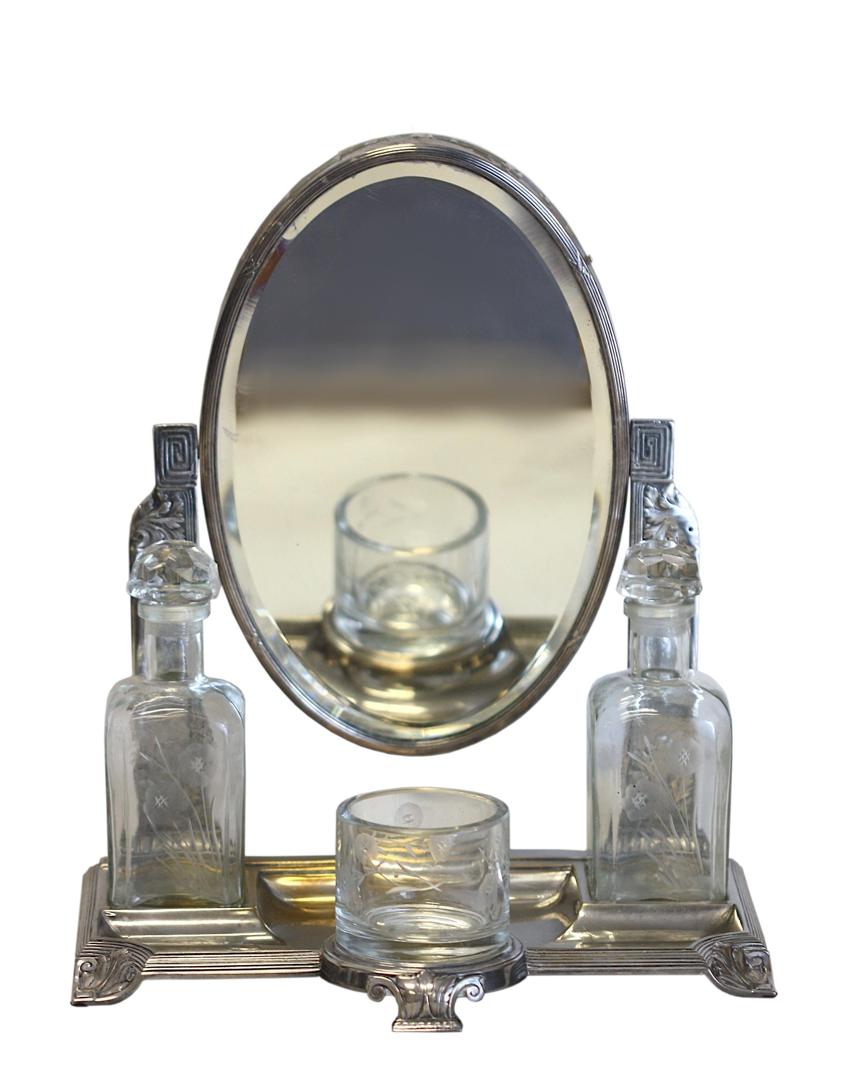 
Art Nouveau Silver Plate & Cut Glass Mirror Dressing Set
1900-1920. The oval mirror pivoted on two foliate and scroll chased supports, the base fitted with two stoppered bottles and a glass. 
Height 14 in. (35.56 cm.), Width 12 in. (30.48 cm.),