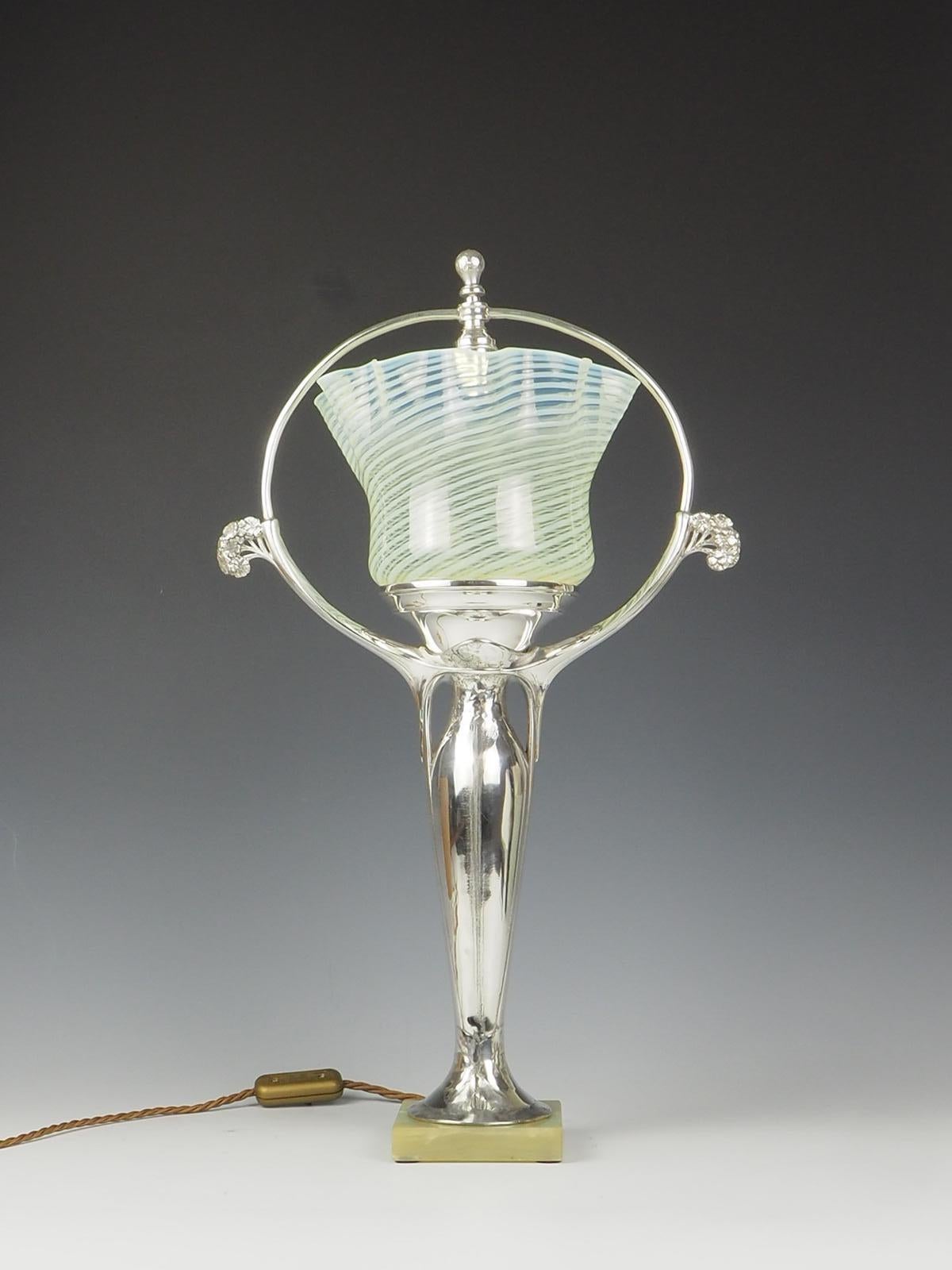 Description

Exquisite Art Nouveau Silver Plate Table Lamp featuring a Vaseline Shade signed by M.C. The lamp stands elegantly on a marble base, adding a touch of sophistication.

The unique design of a tree shape adds a whimsical and artistic