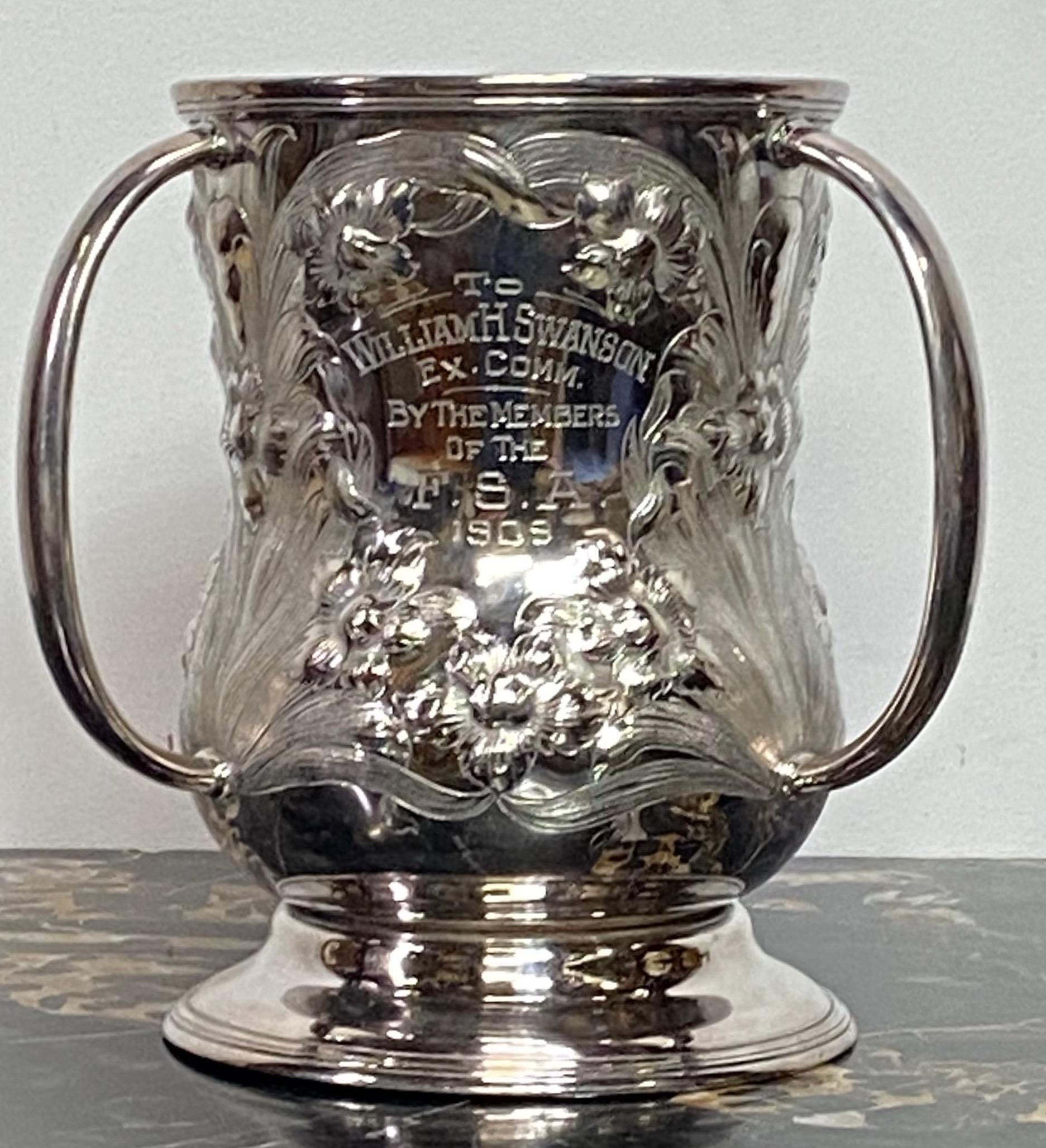 Art Nouveau style commemorative three handled loving cup trophy with raised floral decoration. This would also make an interesting wine or champagne cooler or as always a perfect vase.
Reads: To William H Swanson, Ex. Comm., By the Members of the