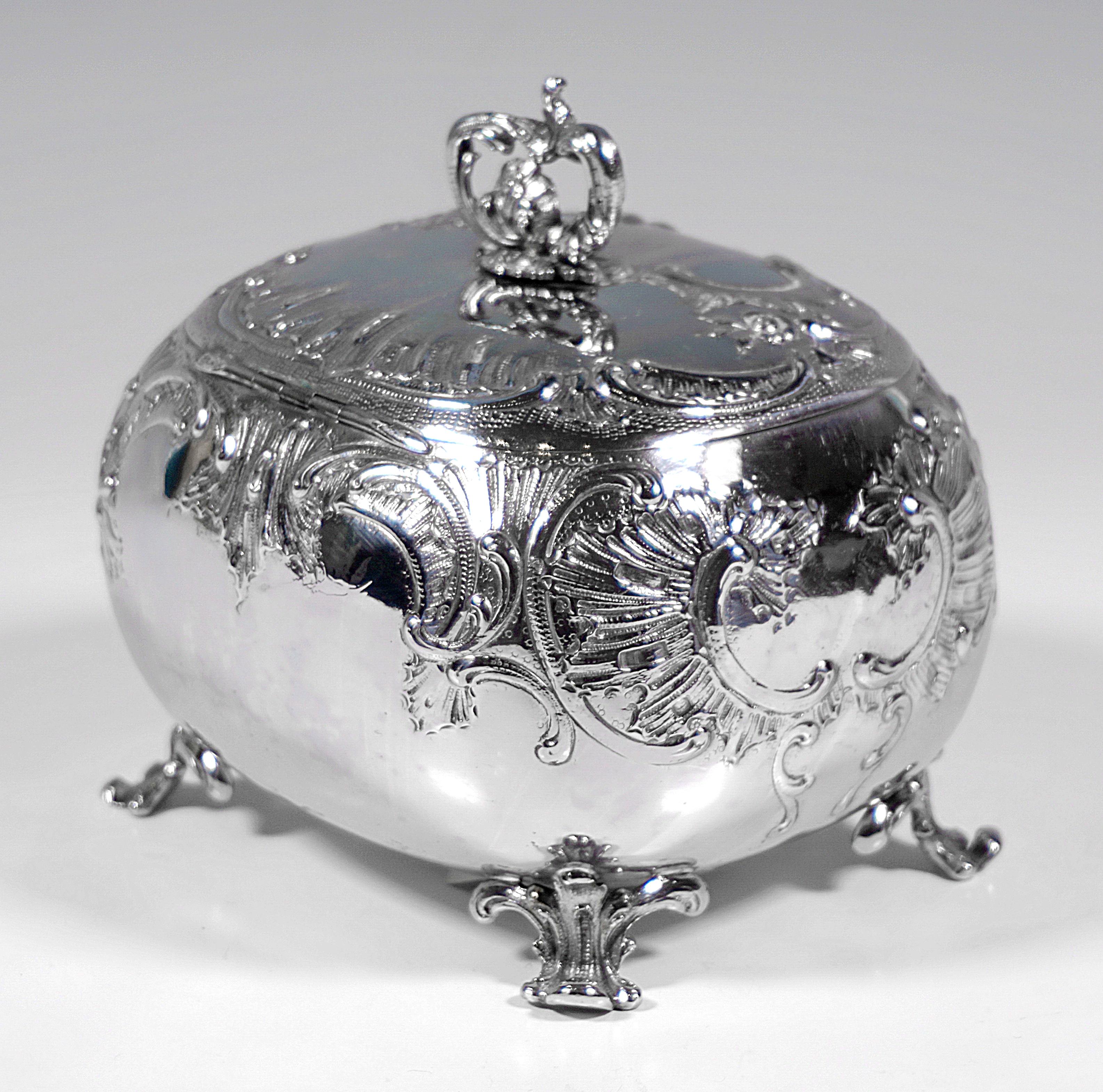 Art Nouveau sugar bowl of oval, rounded form, standing on four rocaille feet, rocaille decoration in relief on the wall and hinged lid, sculpted, towering rocaille volutes forming a handle, discreet monogram, key present.

Hallmarks:
- Diana's head